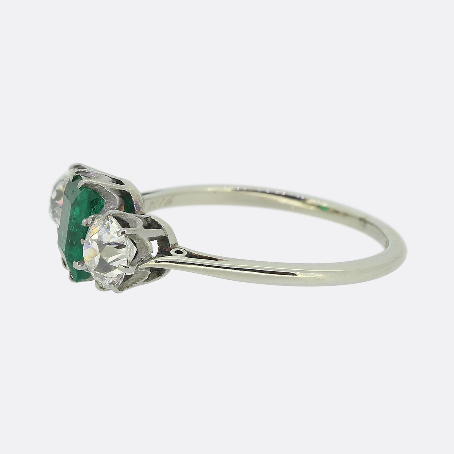 Here we have an outstanding three-stone ring. This elegant piece has been crafted from both 18ct white gold and platinum and showcases a single square cushion cut emerald at the centre of the face. This principal stone is of Colombian origin and