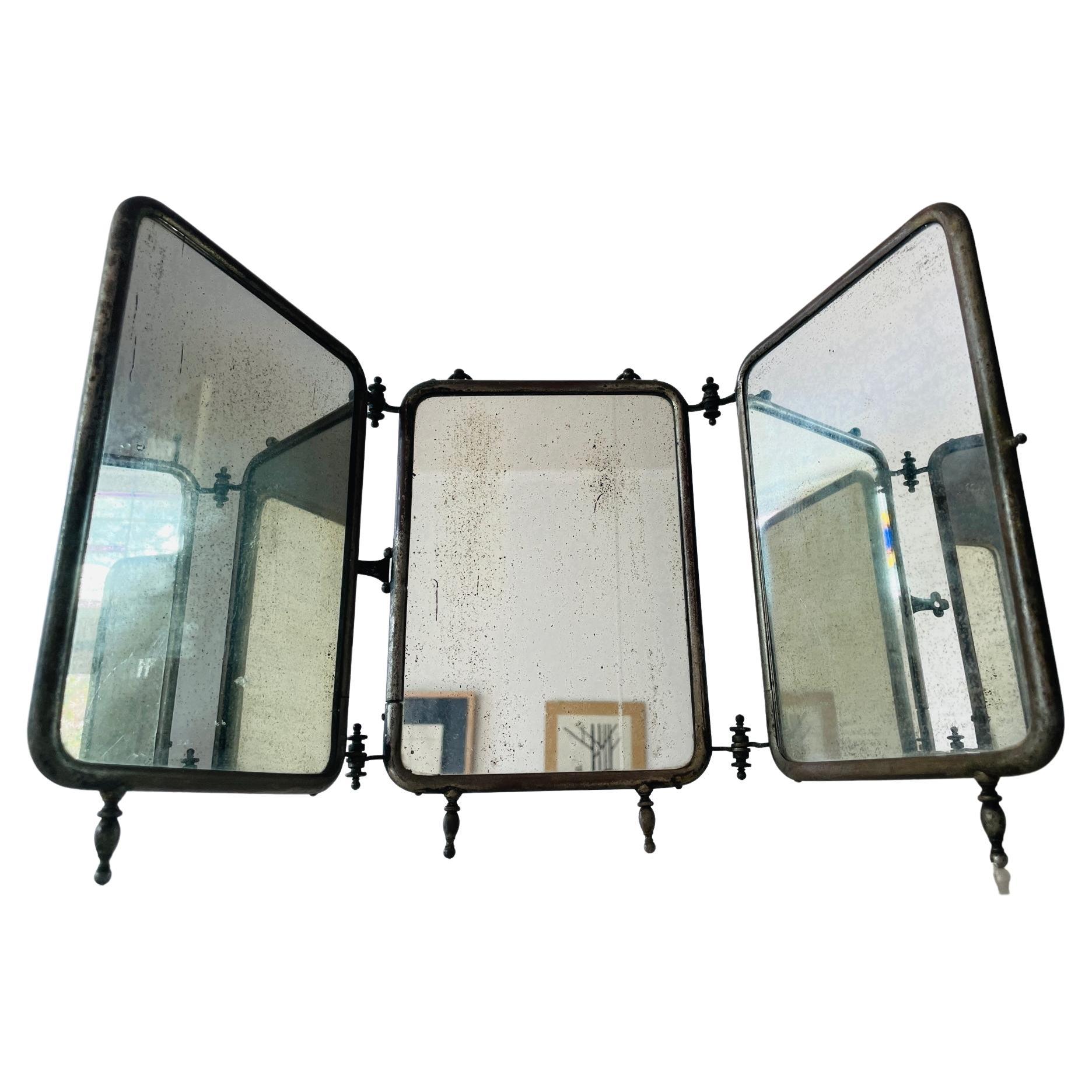 An antique barber's shaving mirror with three mirrors set in a tubular, nickel frames and leather backed. Held together by organic, curved hinges and metal chain. Folds up neatly into one compact piece. In beautiful antique condition, a must have