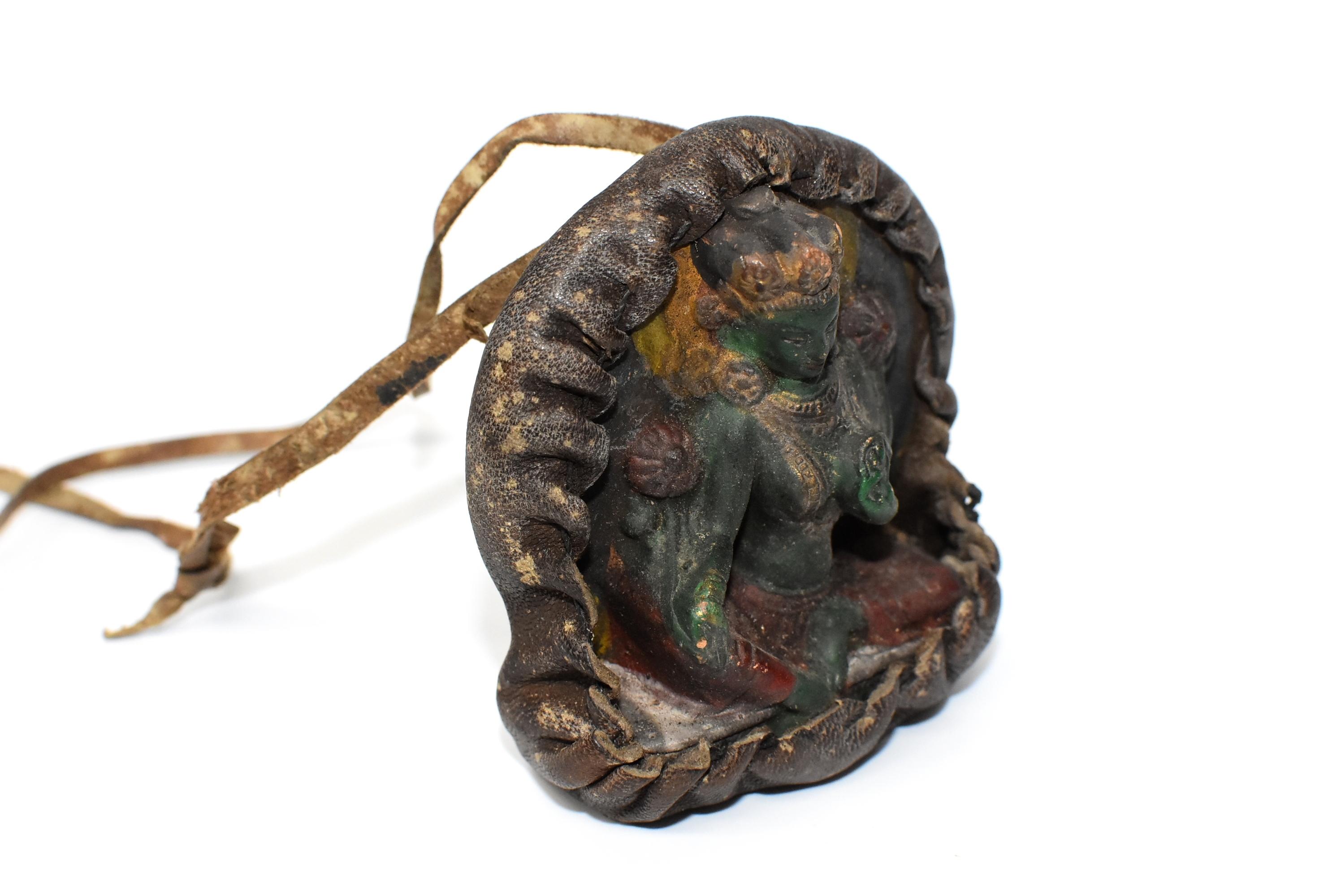 A Tibetan amulet featuring Tara encased in a handmade leather shrine. The Tara is made of terracotta, beautifully crafted displaying well defined facial features, decorated robe and a wonderful smile. Featured is the beloved Green Tara who is always