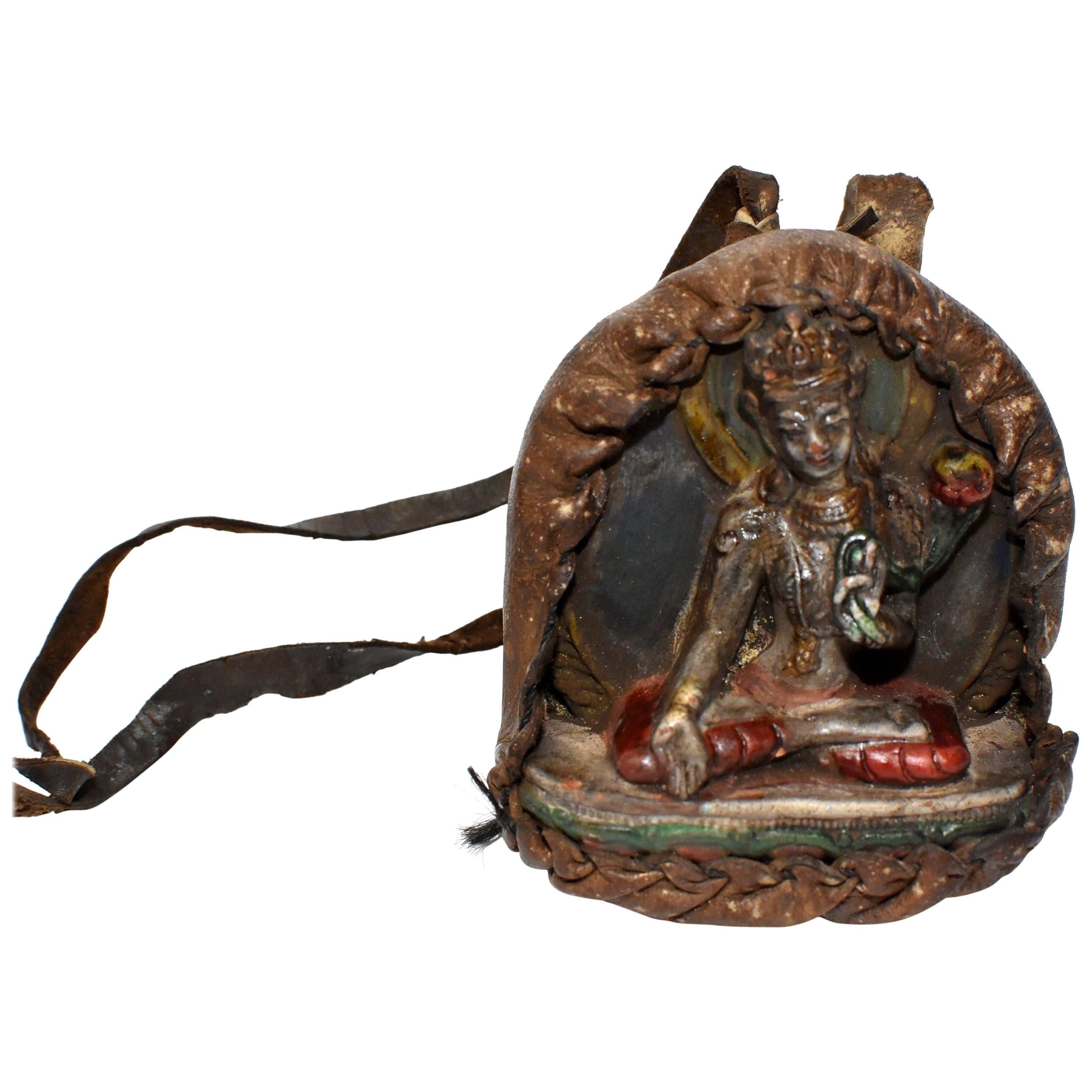 A Tibetan amulet featuring Tara encased in a handmade leather shrine. The Tara is made of terracotta, beautifully crafted displaying well defined facial features, decorated robe and a wonderful smile. Unique silver finish. Such an amulet is