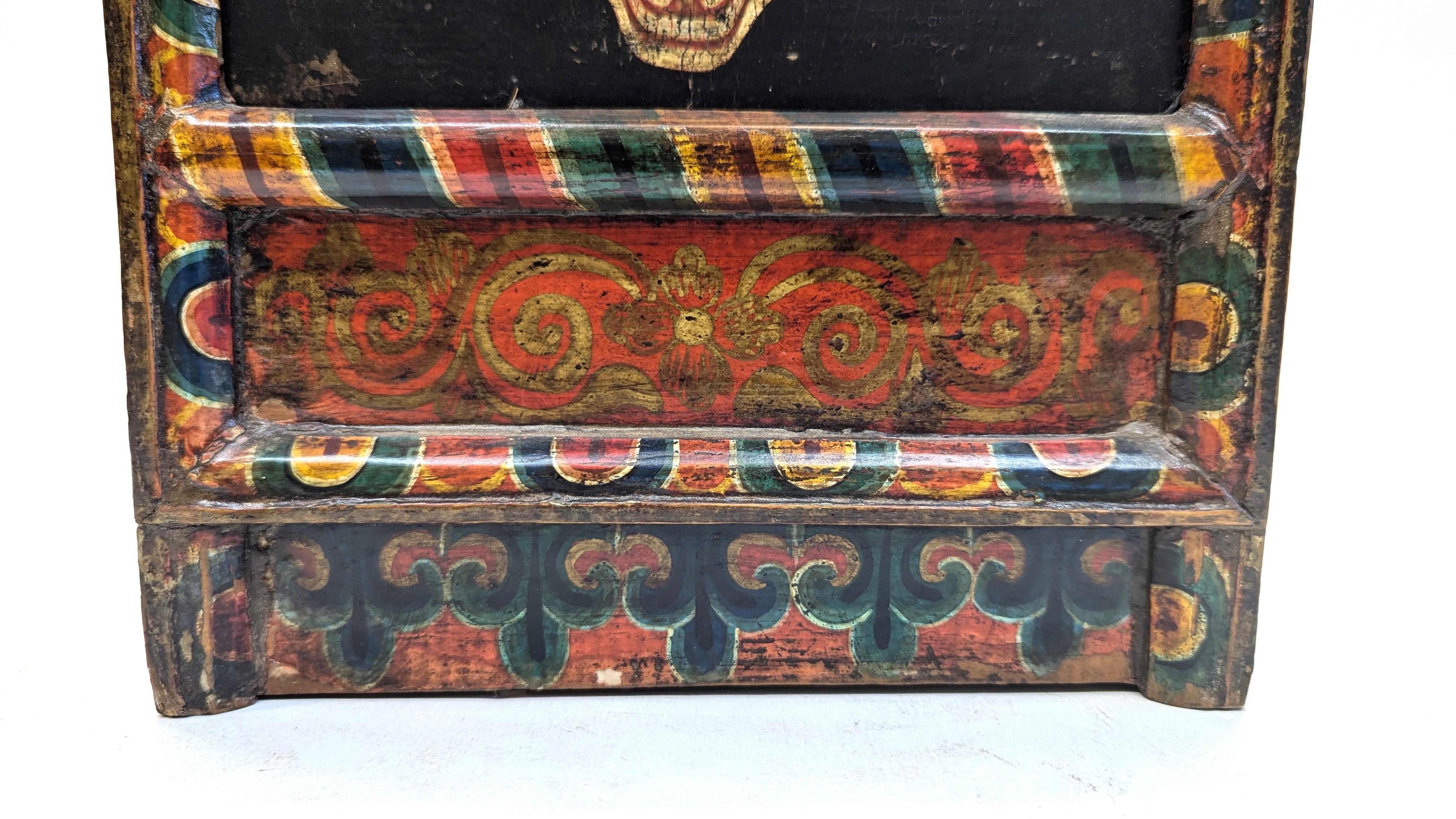 Early to middle 20th century Tibetan Buddha Box. Hand painted and hand carved.  Three Jewels of Buddhism are painted in the center of the top as Buddhist symbol Triratna.  Adorned with painting of Mahakala Skelton faces each toped with a Tibetan