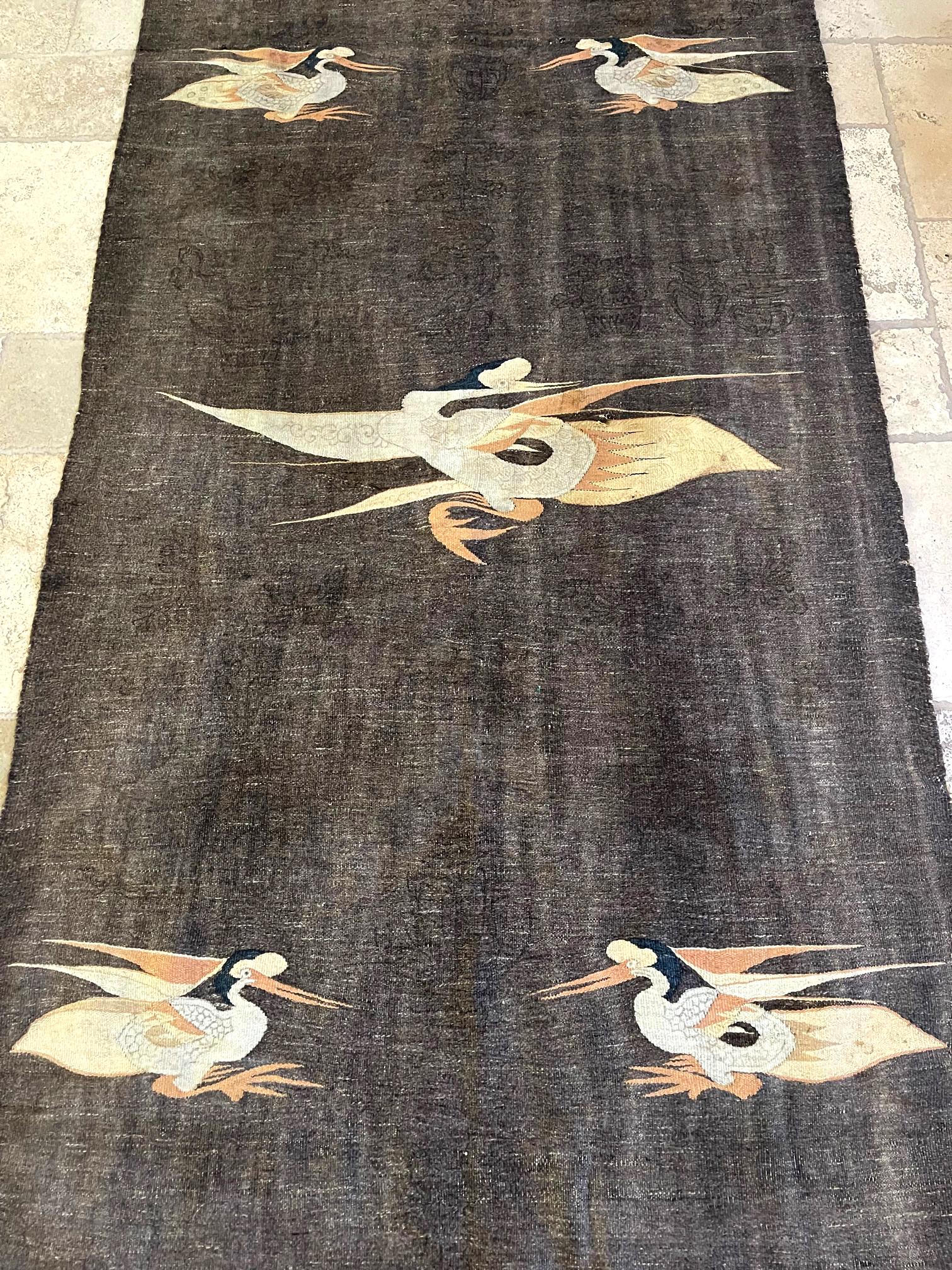 A large wall hanging tapestry, adapted from its previous life as a curtain panel in Tibet (circa late 19th to early 20th century). The textile panel was woven from a coarse wool material (may be yak) and features five stylized crane motifs in subtly