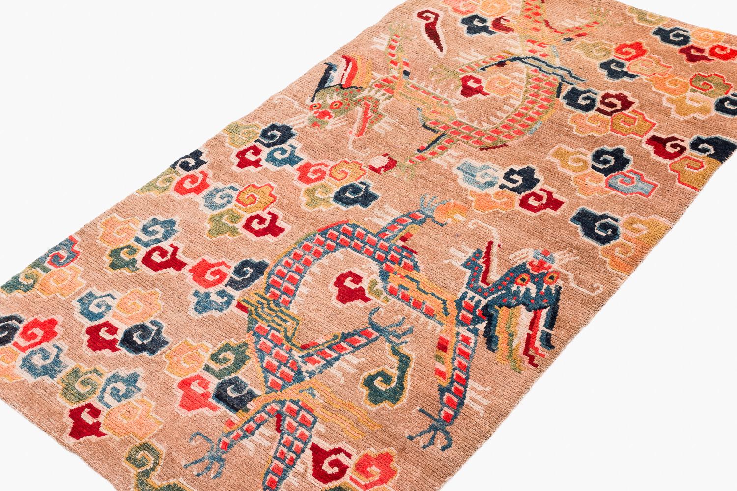 Antigua alfombra tibetana Khaden con dos hermosos dragones y un salvaje surtido de nubes de colores pastel sobre un fondo neutro tostado. Esta alfombra presenta todos tintes vegetales y su composición es inusual, ya que no es típica de la época ni