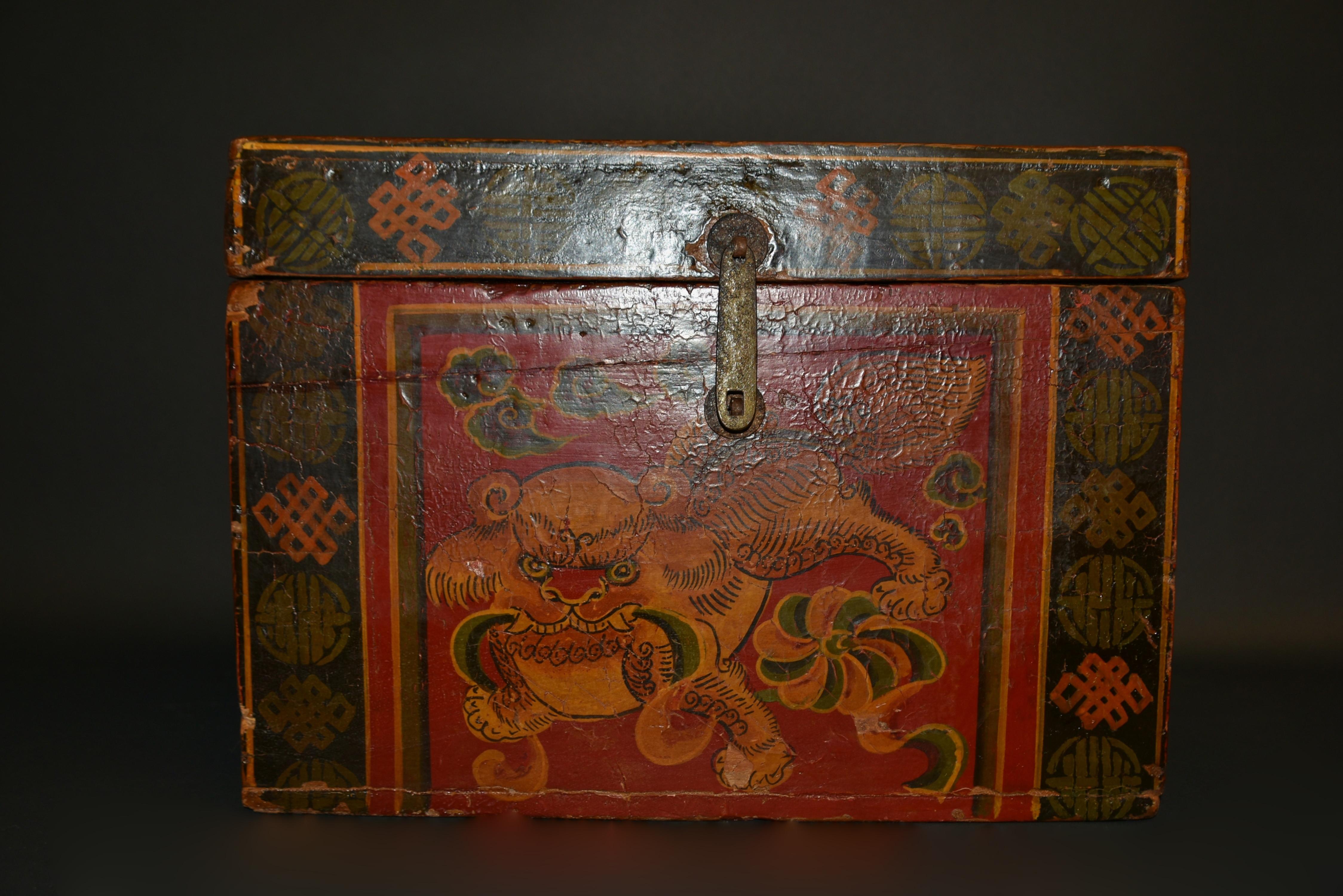 One of our most adorable foo dogs among our limited antique 19th century foo dog box collection. The large head with big innocent eyes and red lips is framed by curled mane. Fleshy paws pressing into the ground, firmly holding a waving ribbon. A