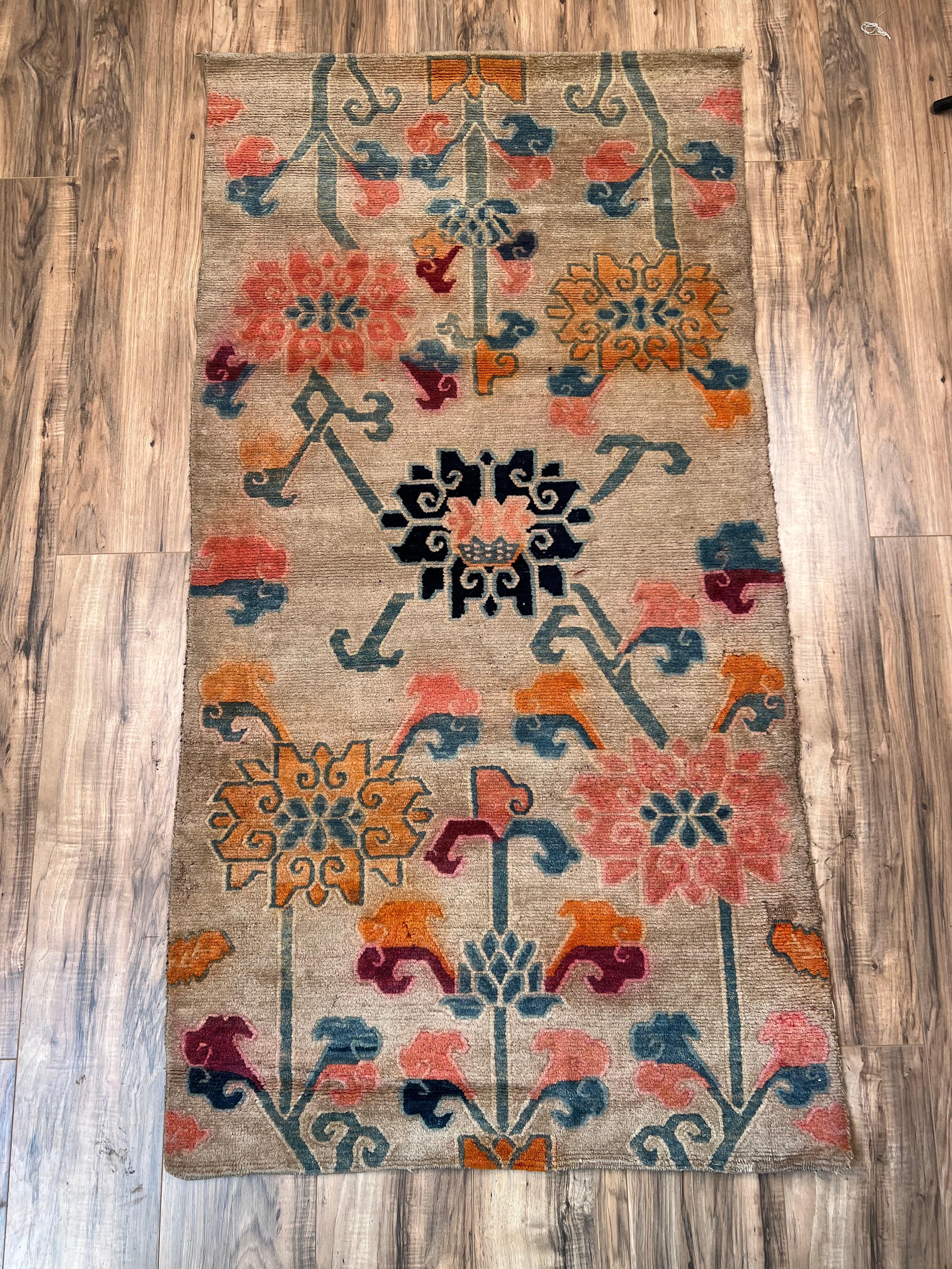Ce tapis tibétain Khaden antique unique, tissé au début du XXe siècle, présente une rare fusion du tissage himalayen traditionnel avec des motifs floraux plus communément associés aux tapis anatoliens Oushak. Les formes florales à grande échelle,