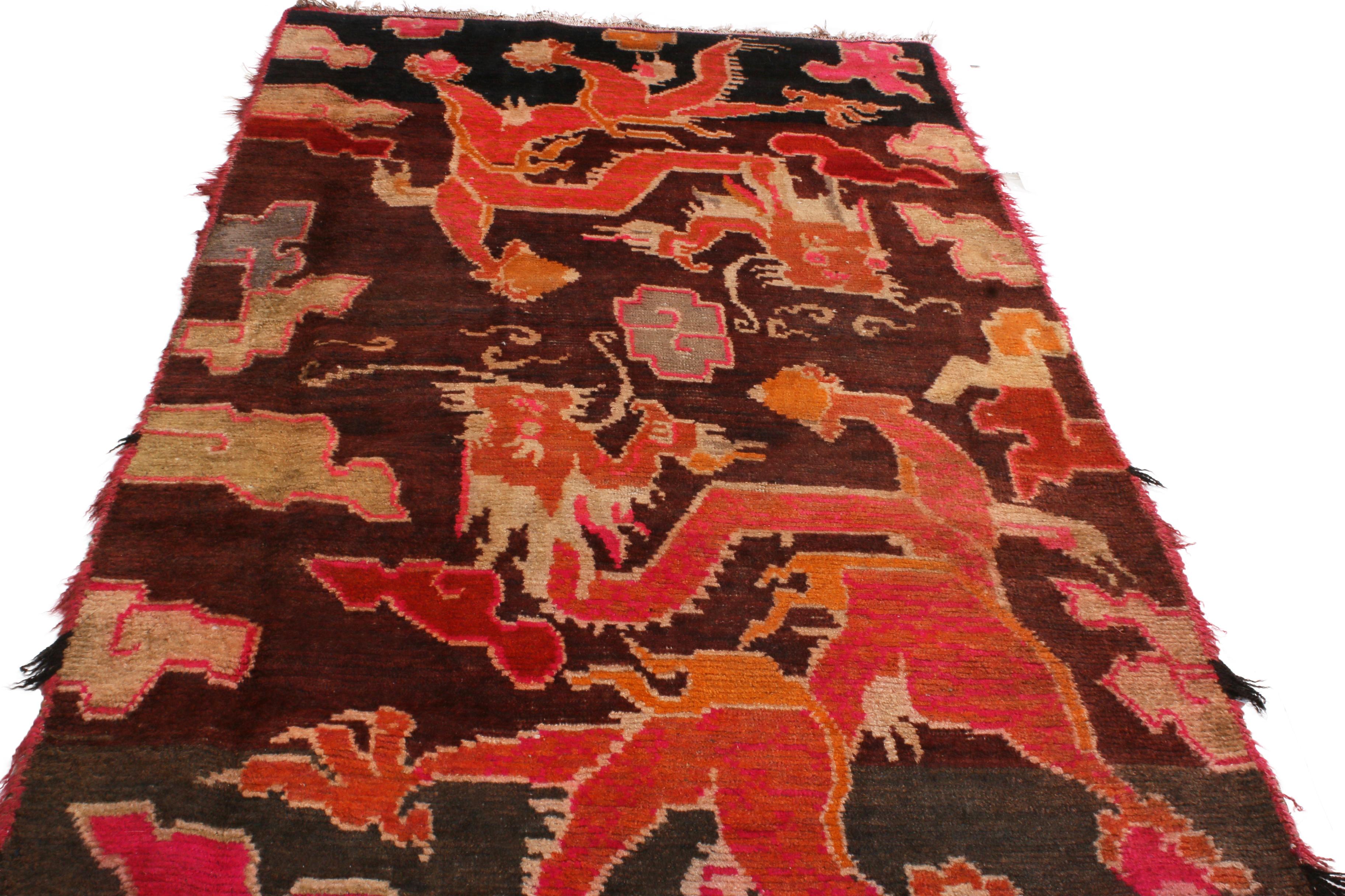 Hand knotted in high-quality wool originating from Tibet between 1890-1900, this antique transitional rug employs a culturally iconic field design portraying mirrored dragons and ruyi clouds with a unique combination of vibrant orange, pink, and