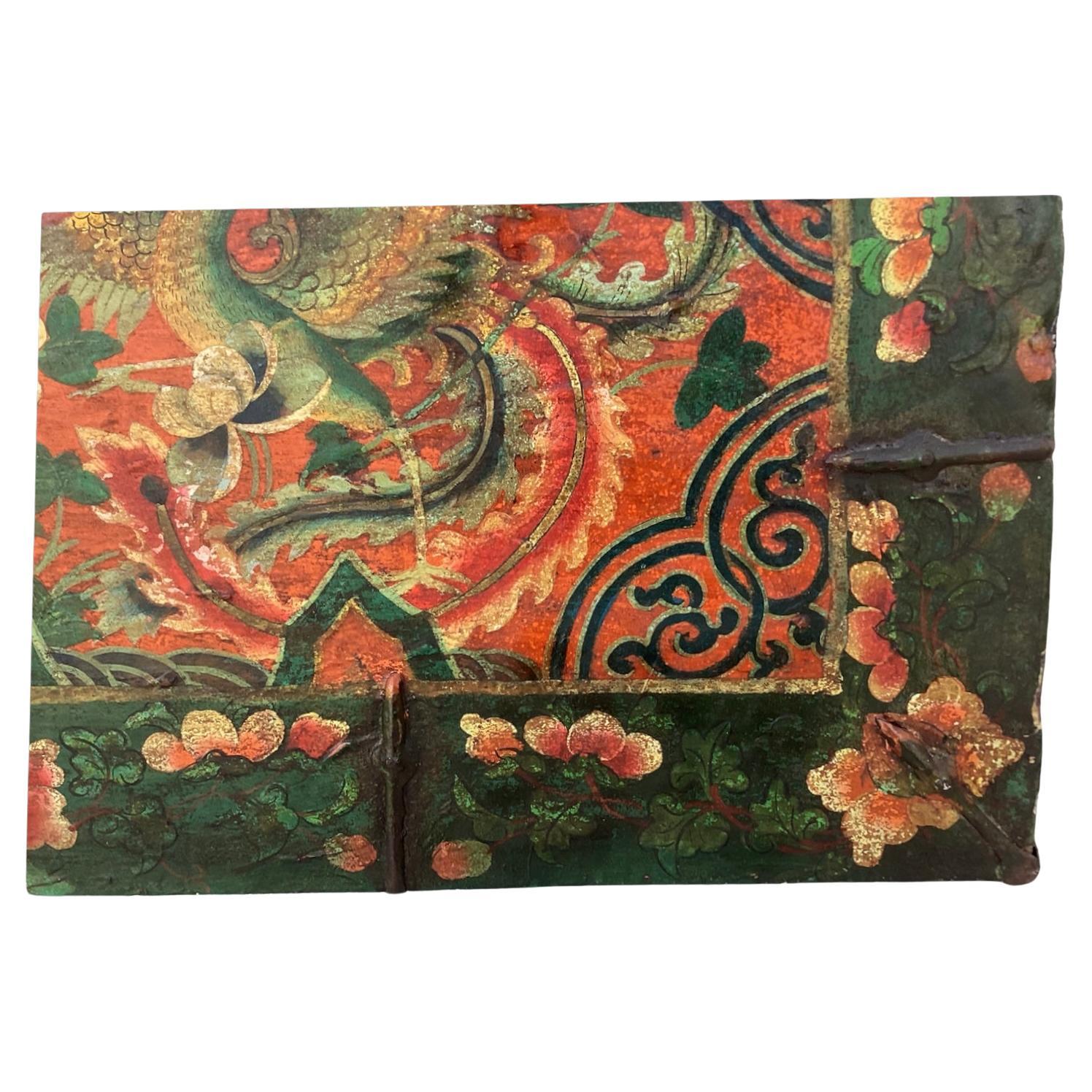 Antike tibetische Truhe, schön gealtertes bemaltes Leder mit originalen Eisenbeschlägen. Die Truhe hat einen geräumigen Innenraum aus Holz, der viel Stauraum bietet. Außen sind mehrfarbig bemalte Drachen und asiatische Blumen in roten, grünen und