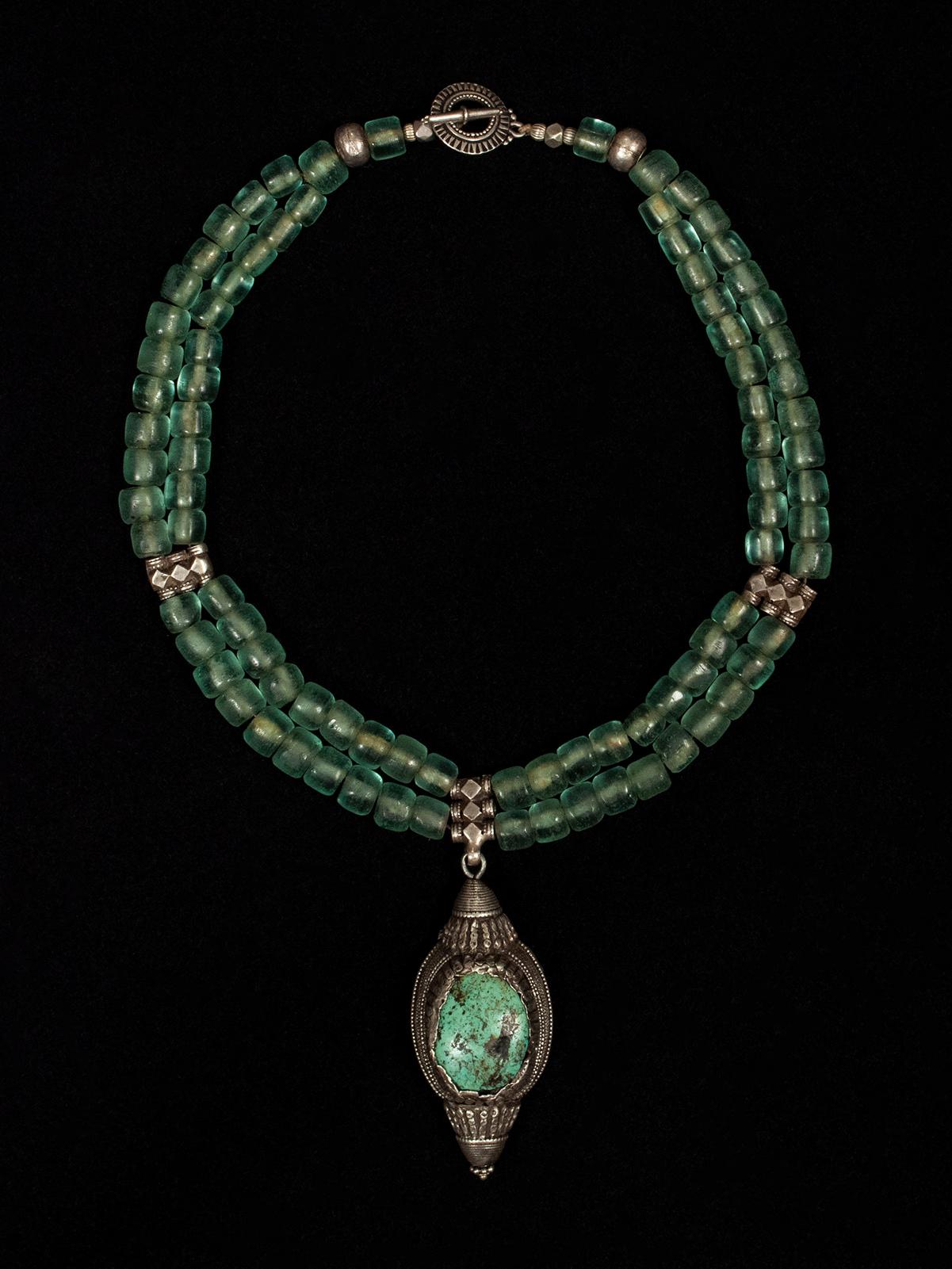 Antique Tibetan turquoise and silver bead pendant contemporary necklace

An antique Tibetan turquoise and silver hair ornament anchors a necklace of gorgeous antique green glass beads. A modern silver clasp finishes the piece, which has an interior