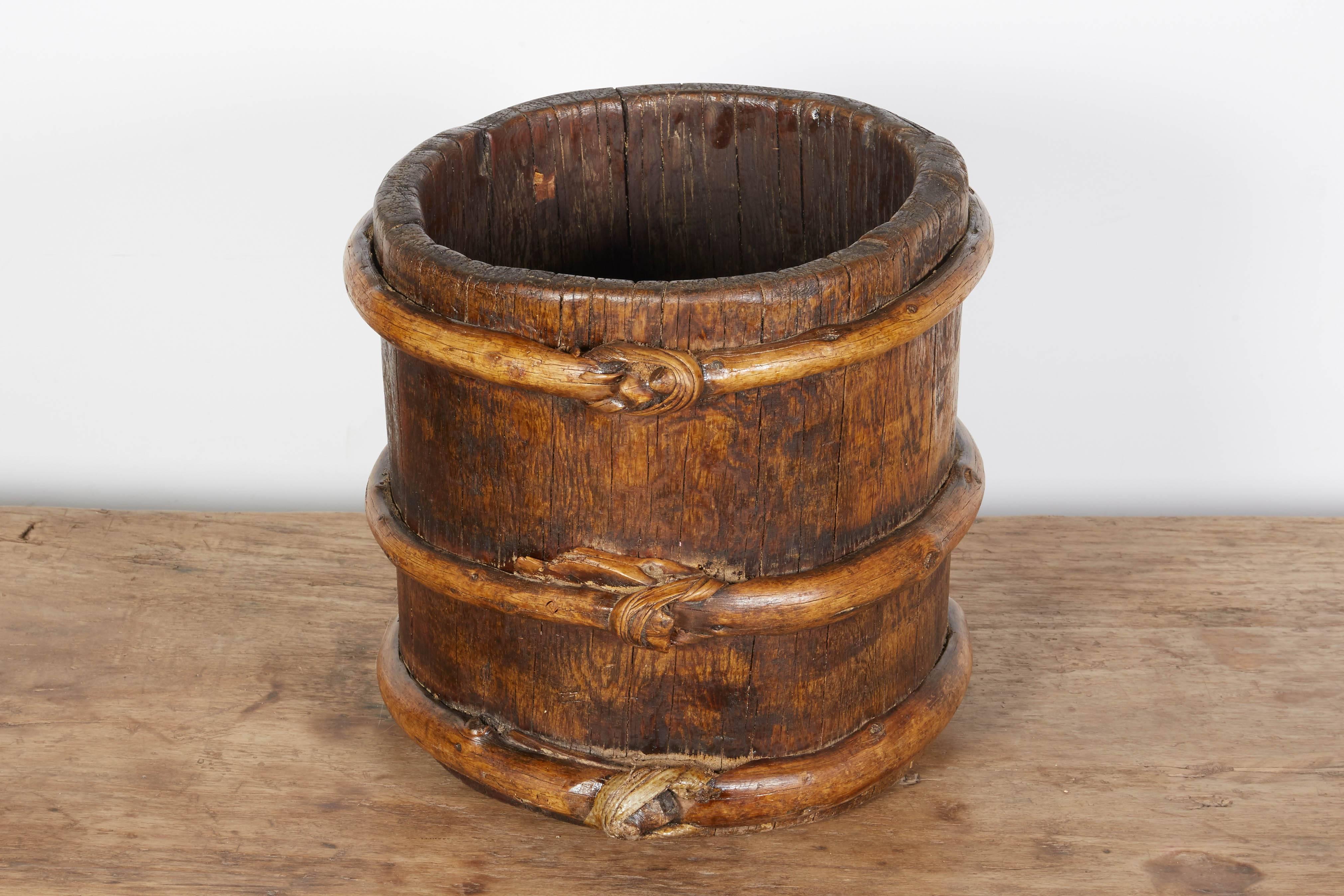 An early 20th century wooden Tibetan yak butter churn with striking patina created by years of use with three knotted straps around the circumference of the piece. A very handsome object that can be used in versatile ways, and a great conversation