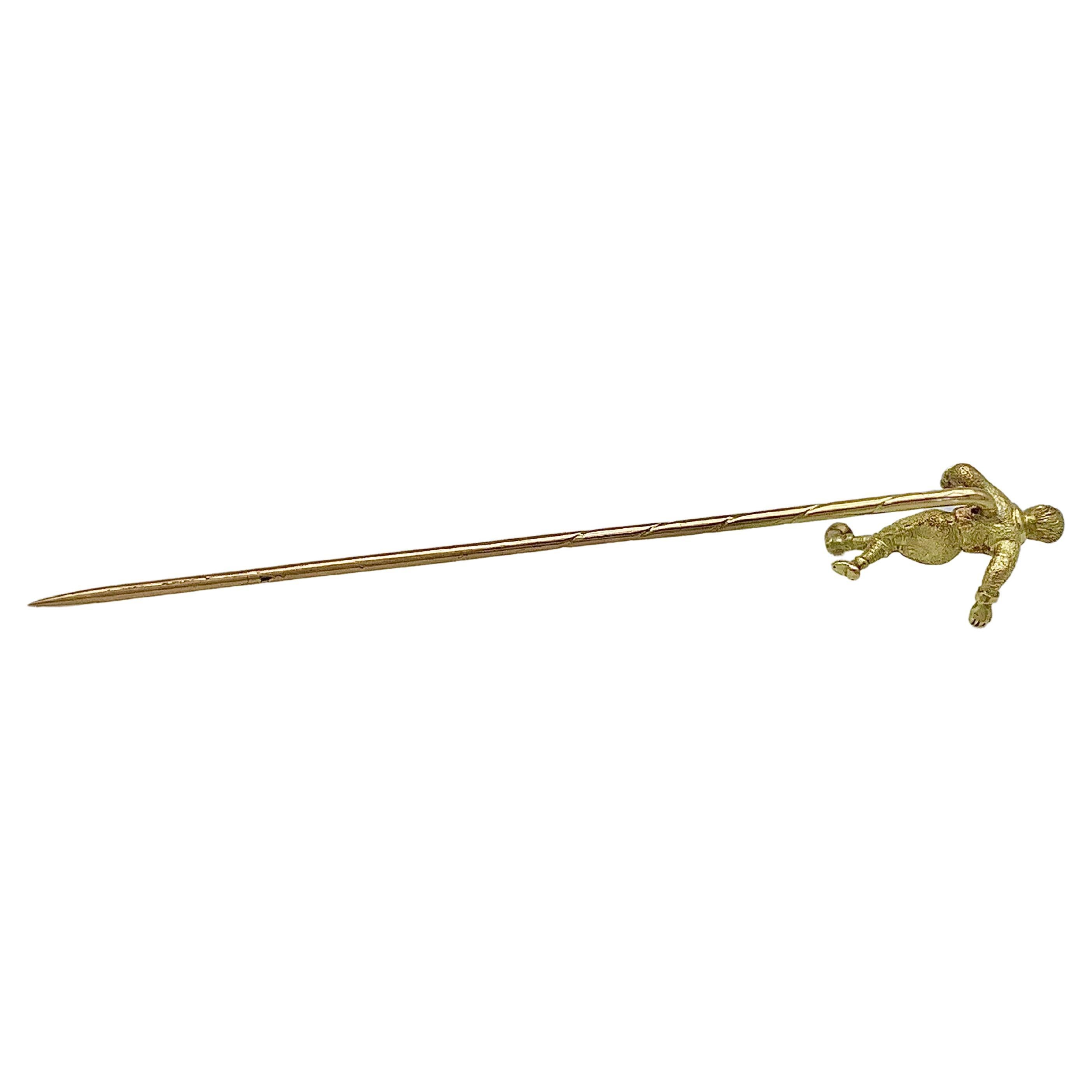 This charming stick pin of a football / soccer player has been crafted from 14 karat gold. The pin is impressed with the Austrian hallmark for 14 karat gold in use from 1901 - 1921. The sportsman wears a long sleeve shirt with collar, shorts, knee