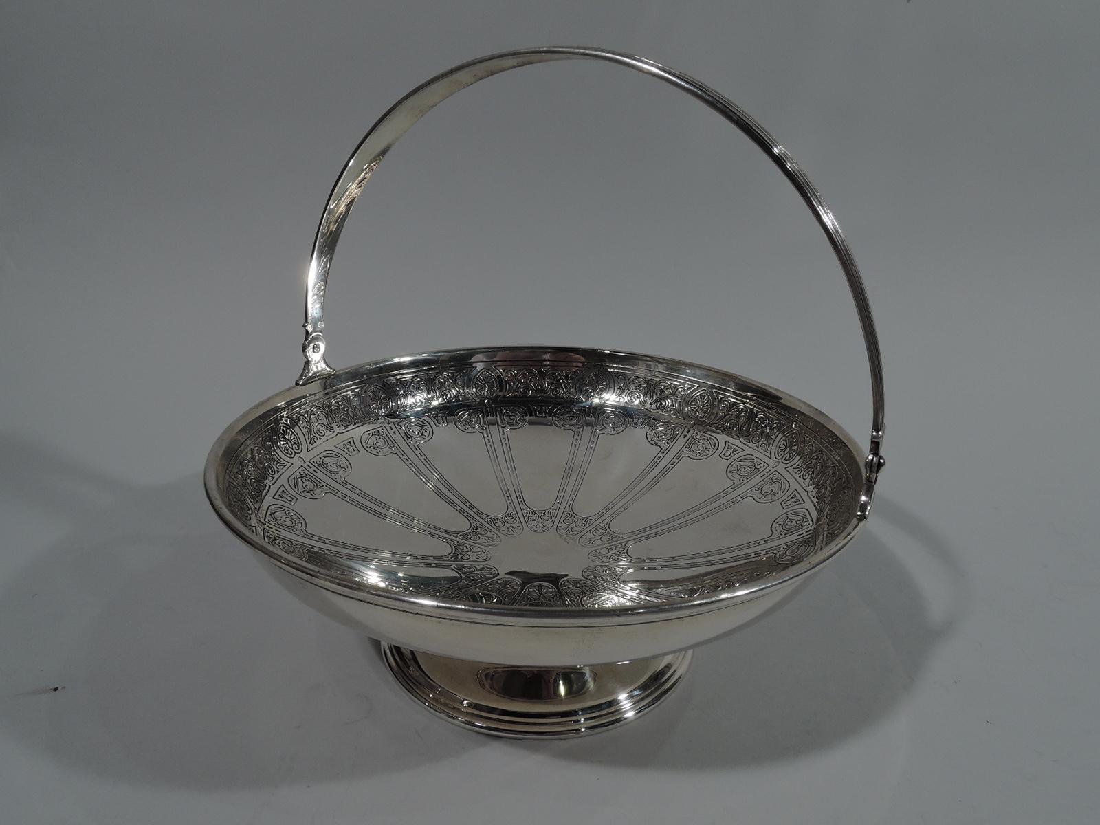 Aesthetic sterling silver basket bowl. Made by Tiffany & Co. in New York, circa 1912. Wide and curved bowl with tapering c-scroll swing handle and raised foot. Stylized acid-etched ornament. On interior vacant centre surrounded by narrow volute