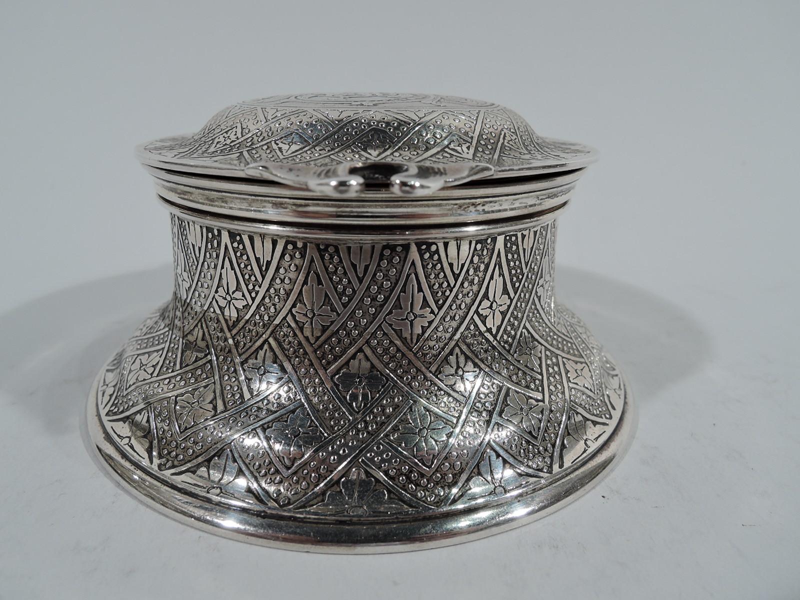 Aesthetic sterling silver inkwell. Made by Tiffany & Co. in New York. Drum-form with spread base. Cover domed with scrolled hinged and tab. Acid-etched ornament: Fluid lattice inset with stylized leaves. Cover top has stylistically-integrated