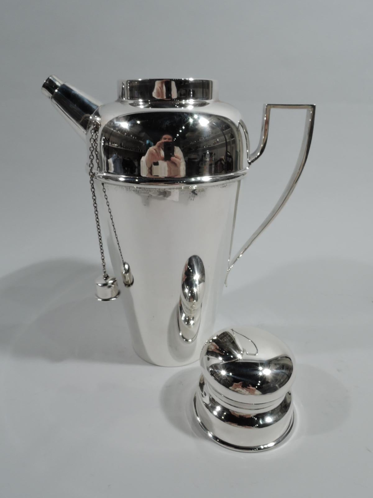 American Art Deco sterling silver cocktail shaker, ca 1925. Retailed by Tiffany & Co. in New York. Straight and tapering bowl, curved shoulder, short inset neck, and sleek scroll-bracket handle. Bun cover and stubby diagonal spout with chained cap.