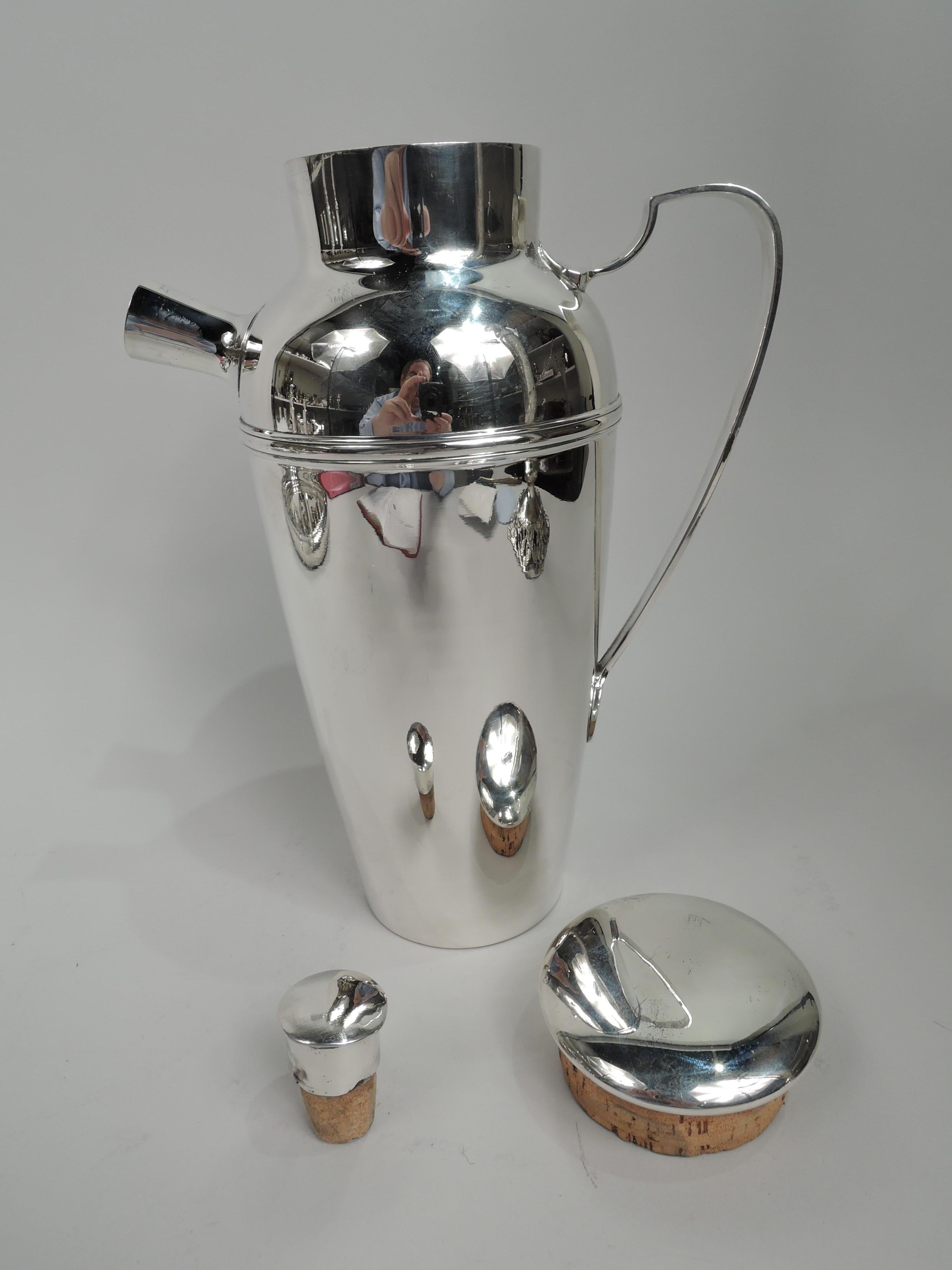Art Deco sterling silver cocktail shaker. Made by Tiffany & Co. in New York, ca 1922. Tapering bowl, curved shoulder, scroll-bracket handle, and short inset neck. Cover has flattish and overhanging top with cork plug. Spout stubby and tapering with