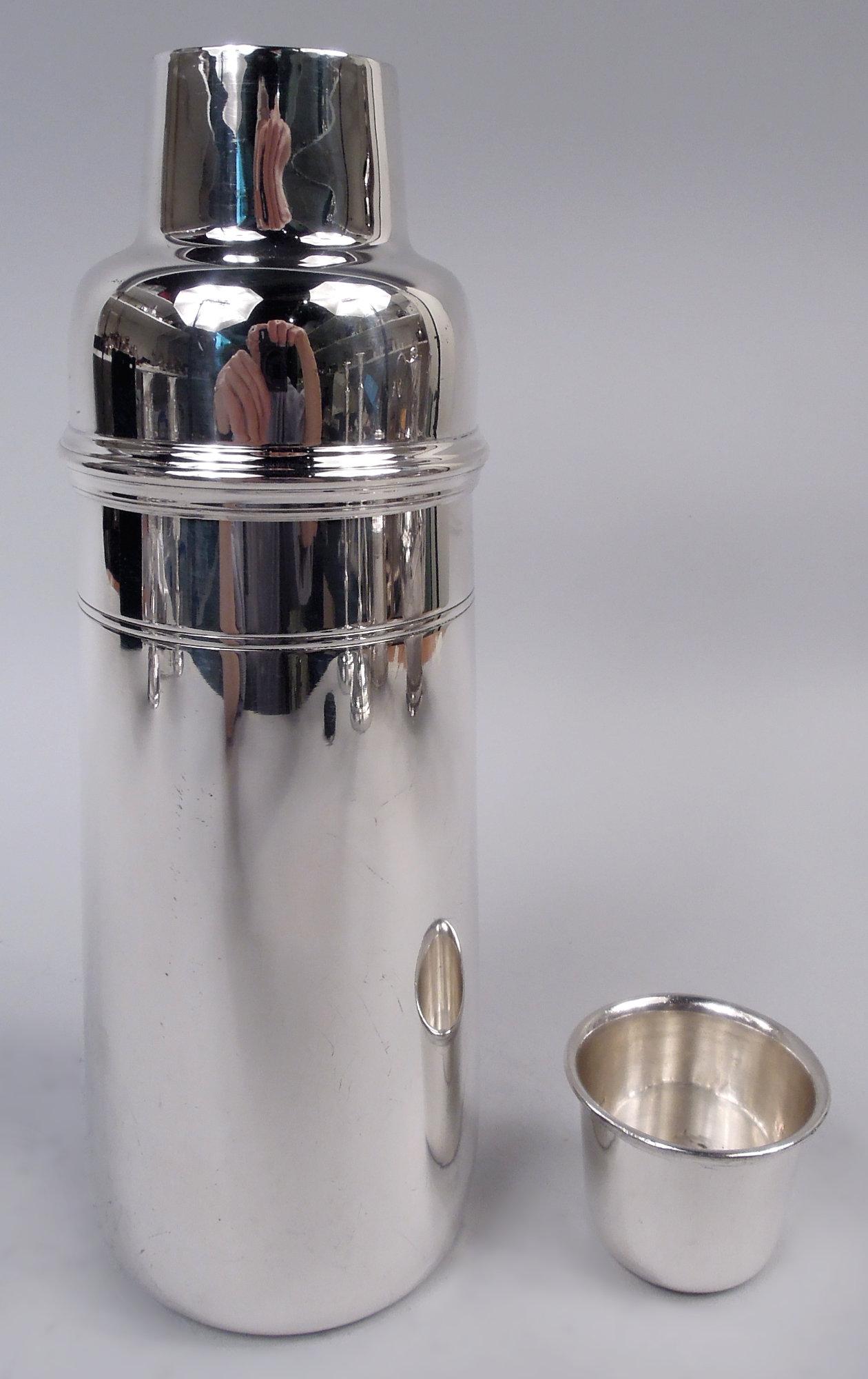 Art Deco sterling silver cocktail shaker. Made by Tiffany & Co. in New York, ca 1917. Sleek bowl with straight and upward tapering sides and curved shoulder; girdled and tooled bands. Neck with built-in ornamental strainer and snug-fitting cap.