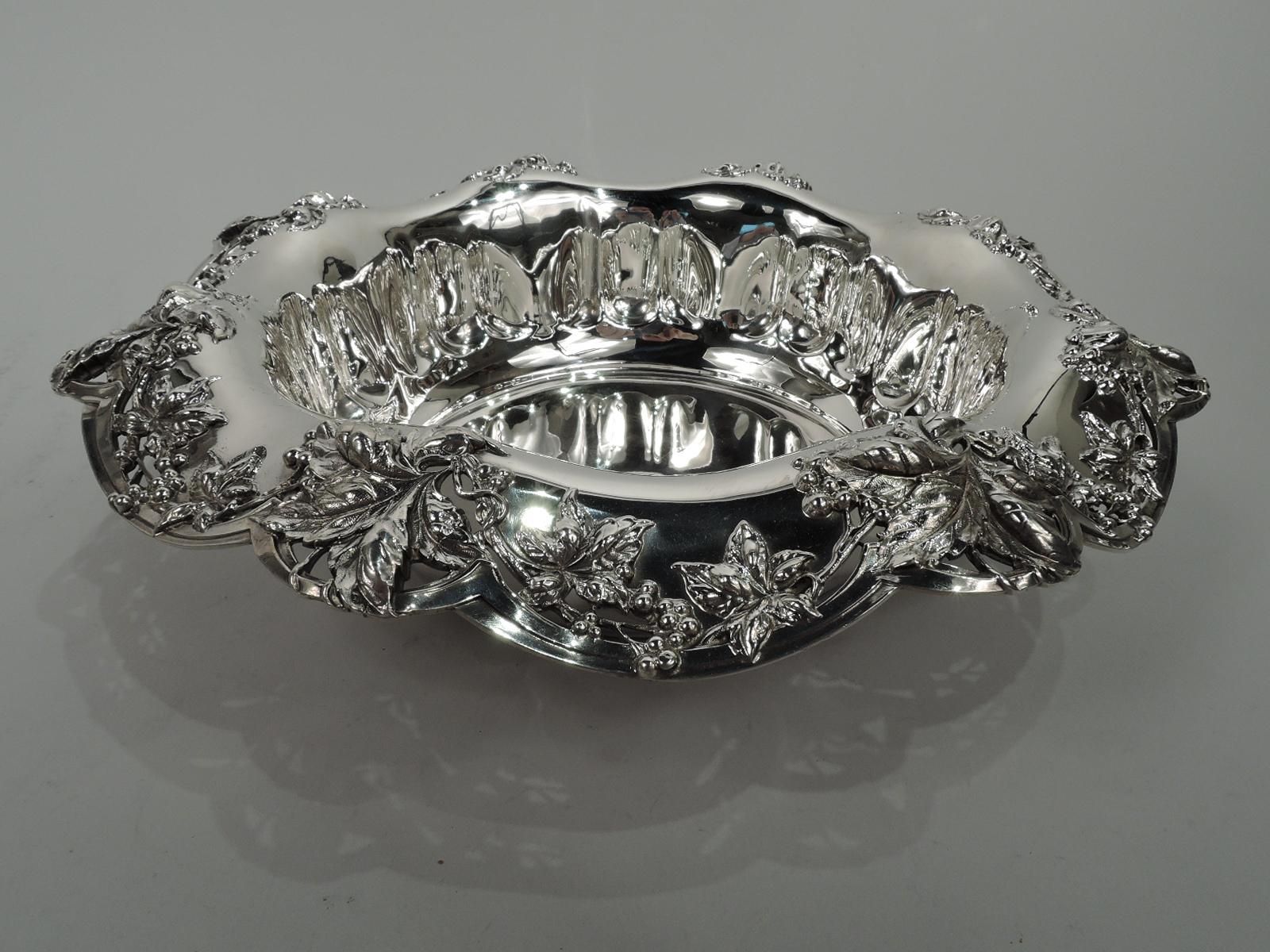 Edwardian Art Nouveau sterling silver bowl. Made by Tiffany & Co. in New York. Round well with abstract egg-and-dart border. Wavy turned town and open shoulder with scalloped rim and applied flowers and leaves. Fully marked including maker’s stamp,