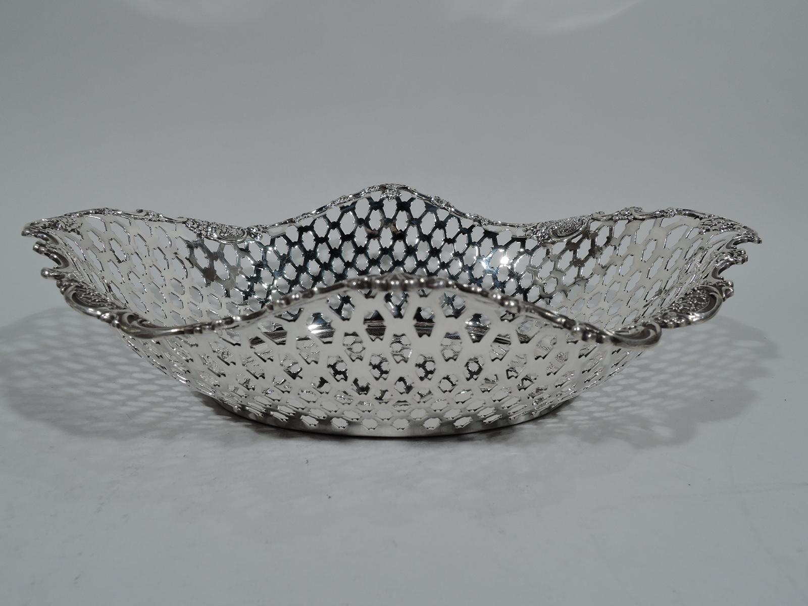 Edwardian sterling silver basket. Made by Tiffany & Co. in New York. Solid oval well. Curved sides with pierced diaper sides and wavy rim with applied scrolls, shells, and flowers. Hallmark includes pattern no. 15517 (first produced in 1902) and