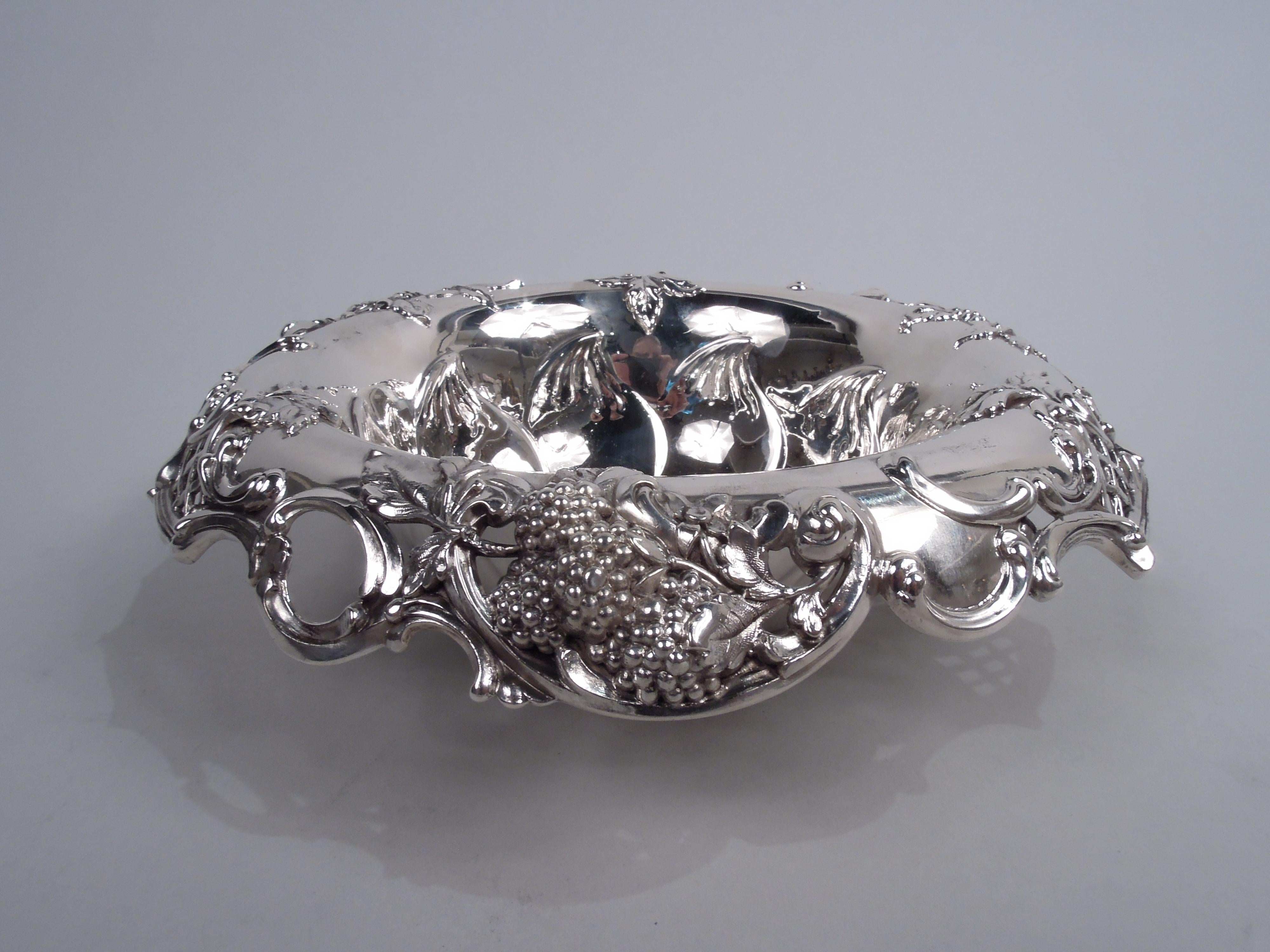 Gilded Age sterling silver blackberry bowl. Made by Tiffany & Co. in New York. Round well; sides tapering with chased outsized leaf border. Scrolled and open turned down rim with applied c-scrolls, leaves, berries, and diaper. A great high-low