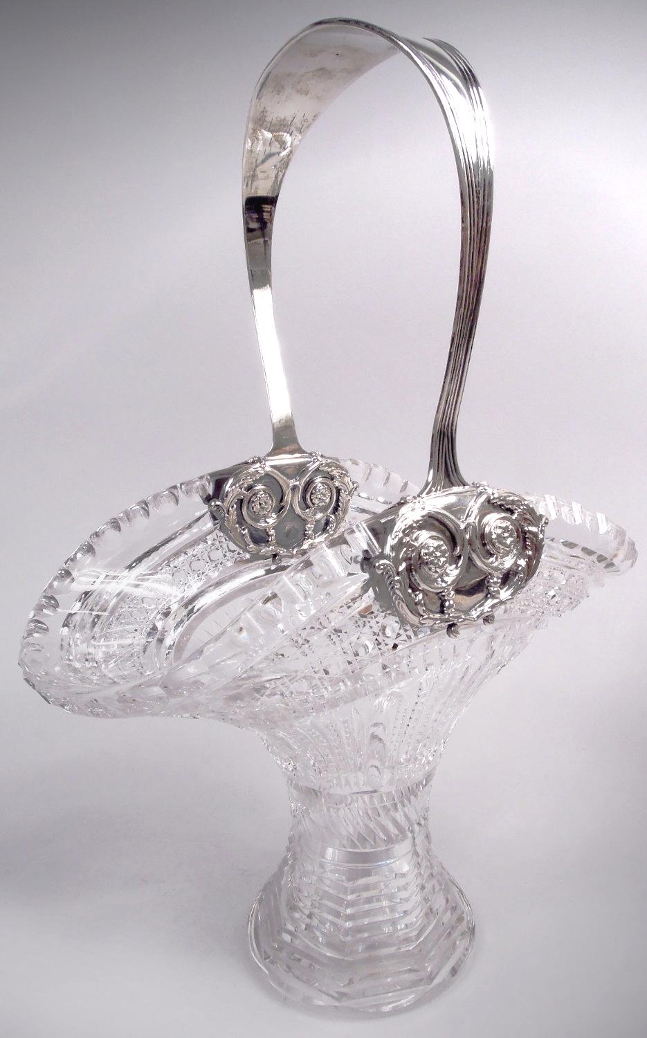 Edwardian Classical brilliant-cut glass basket with sterling silver mounts. Made by Tiffany & Co. in New York, ca 1910. Wide ovoid mouth and faceted and spread cylindrical bowl. Cut diaper, ferns, twisted flutes, scallops, and concentric rings.