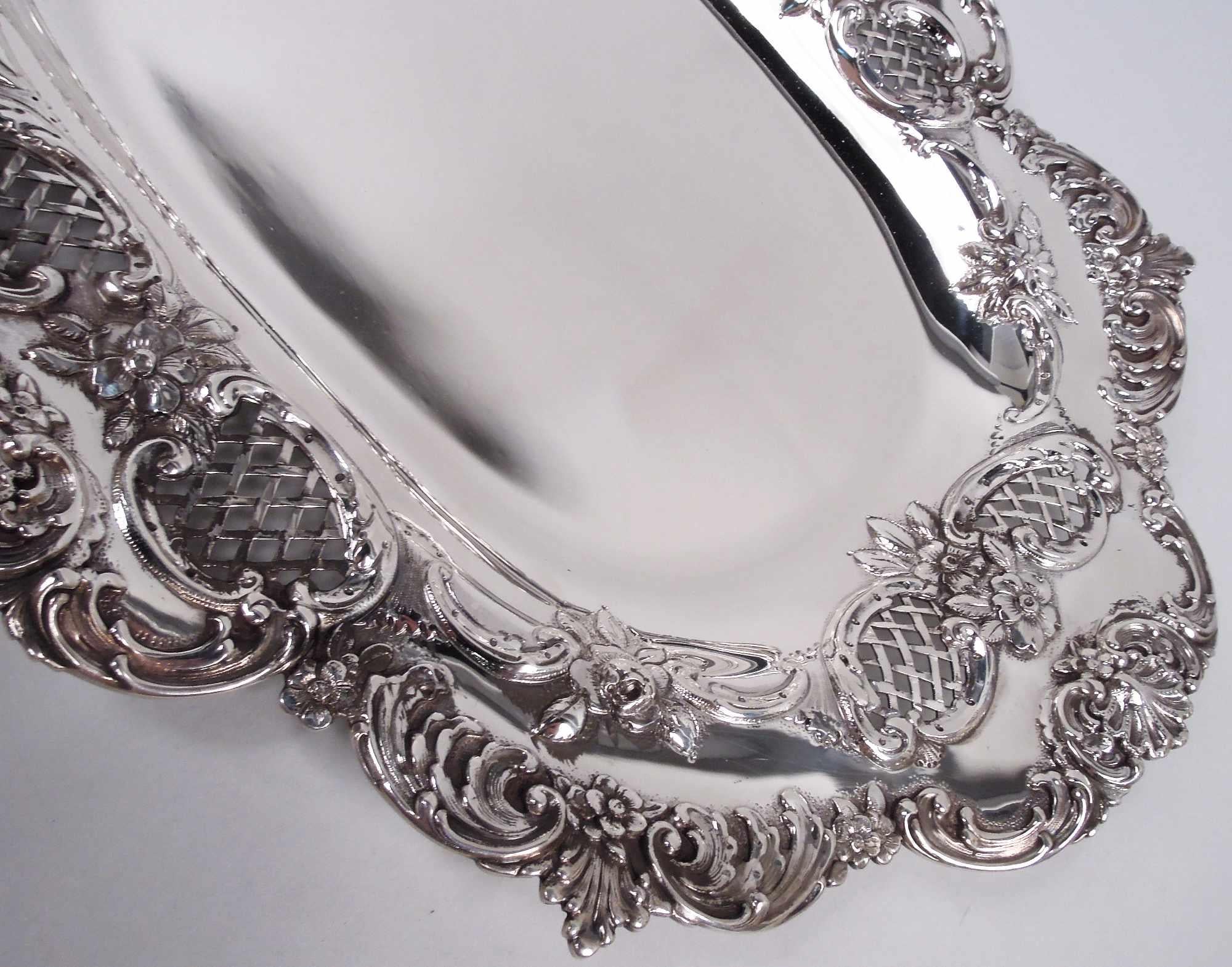 Victorian Classical sterling silver tray. Made by Tiffany & Co. in New York. Solid oval well with curved sides. Shoulder wide with chased flowers, scrolls, and open diaper in scrolled cartouches. Rim has applied leafing scrolls, flowerheads, and