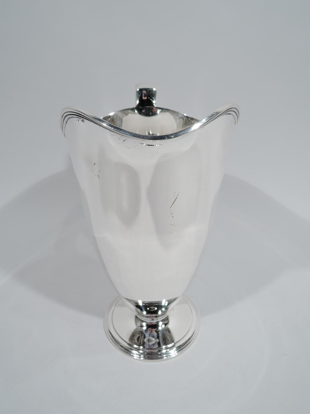 Art Deco Classical sterling silver water pitcher. Made by Tiffany & Co. in New York, ca 1919. Tall and tapering bowl with reeded helmet mouth and scroll bracket handle; foot raised and stepped. Spare and sleek. Fully marked including pattern no.