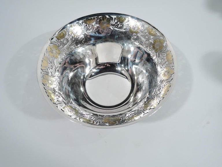 Art Nouveau sterling silver bowl. Made by Tiffany & Co. in New York, circa 1910. Tapering sides and flared rim. Short and straight foot. At rim cutout and engraved border with gilt buttercup-style flowers. Fresh and pretty floral ornament on a spare