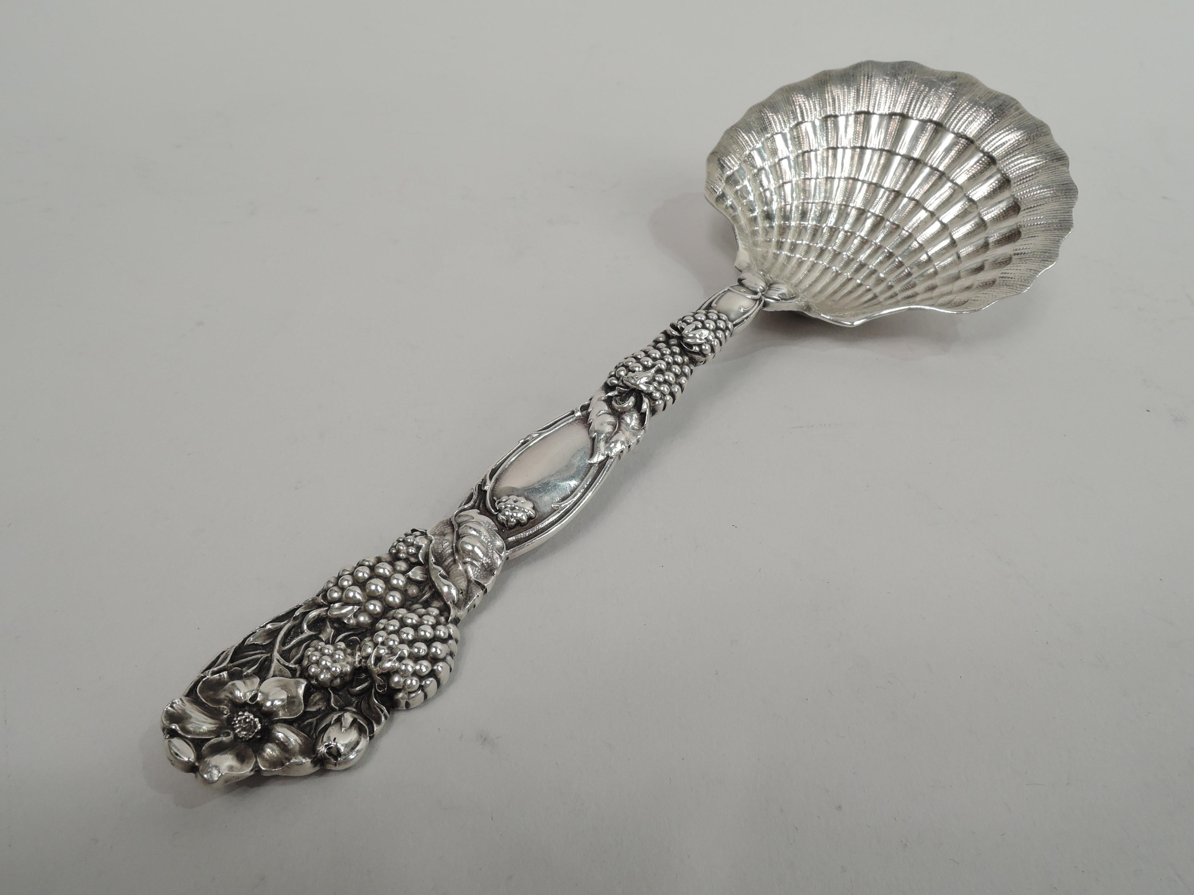 Blackberry sterling silver berry spoon. Made by Tiffany & Co. in New York. Cast double-sided stem with blackberries, leaves, and ovoid frame (vacant). Terminal has flowers with entwined stems. Scallop shell bowl. A gorgeous piece from an 1870s