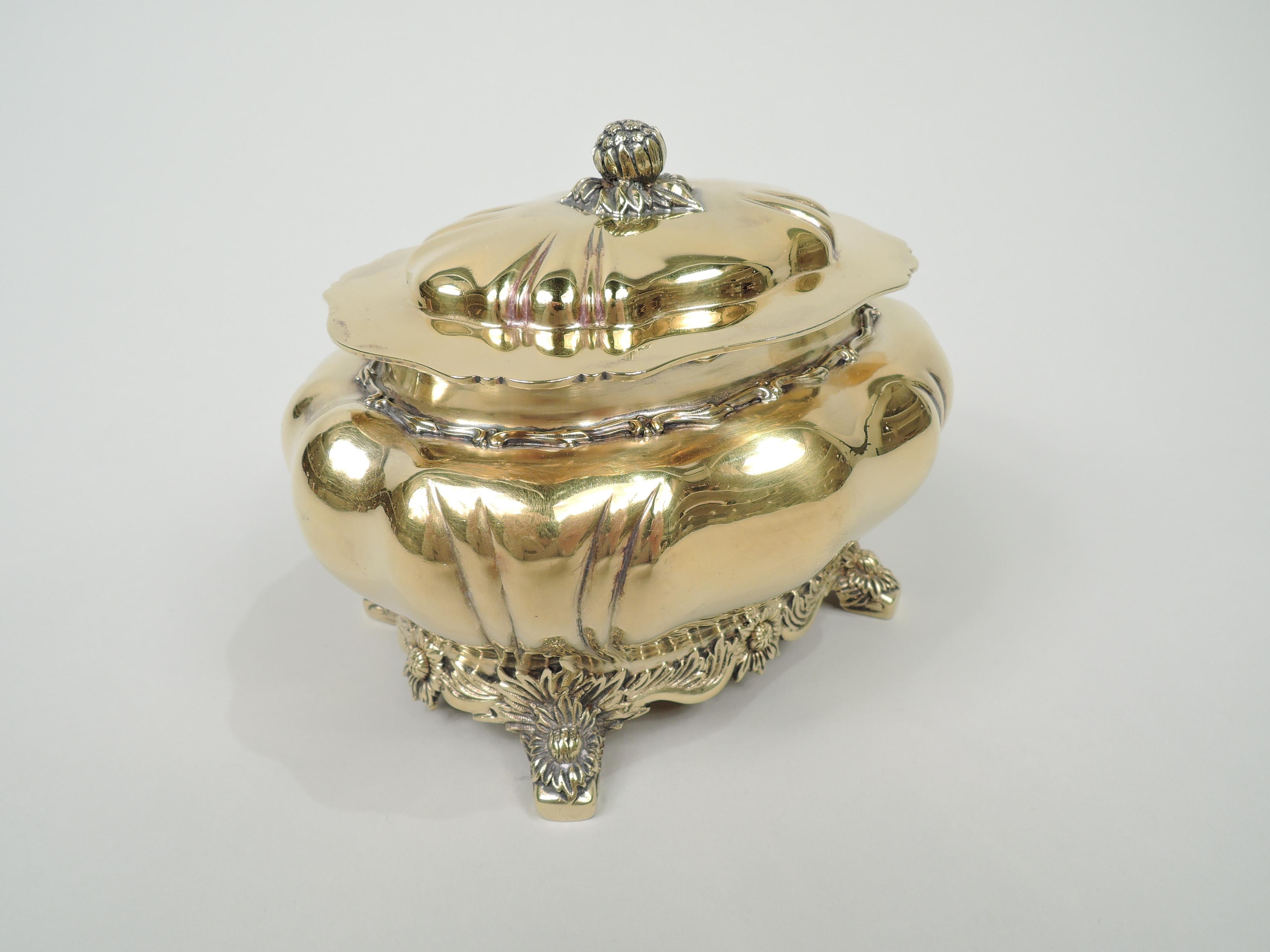 Chrysanthemum gilt sterling silver box. Made by Tiffany & Co. in New York. Traditional lobed and ovoid bowl with short and inset neck and splayed volute scroll supports. Cover hinged and domed with bud finial and plain and scrolled overhanging rim.