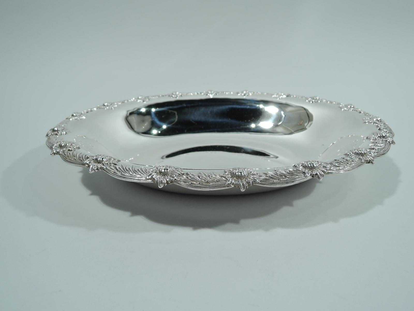 Chrysanthemum sterling silver serving bowl. Made by Tiffany & Co. in New York. Oval well with tapering sides and scalloped rim with applied leaf-and-flower head border in a controlled arrangement. A nice early piece in the historic Japonesque