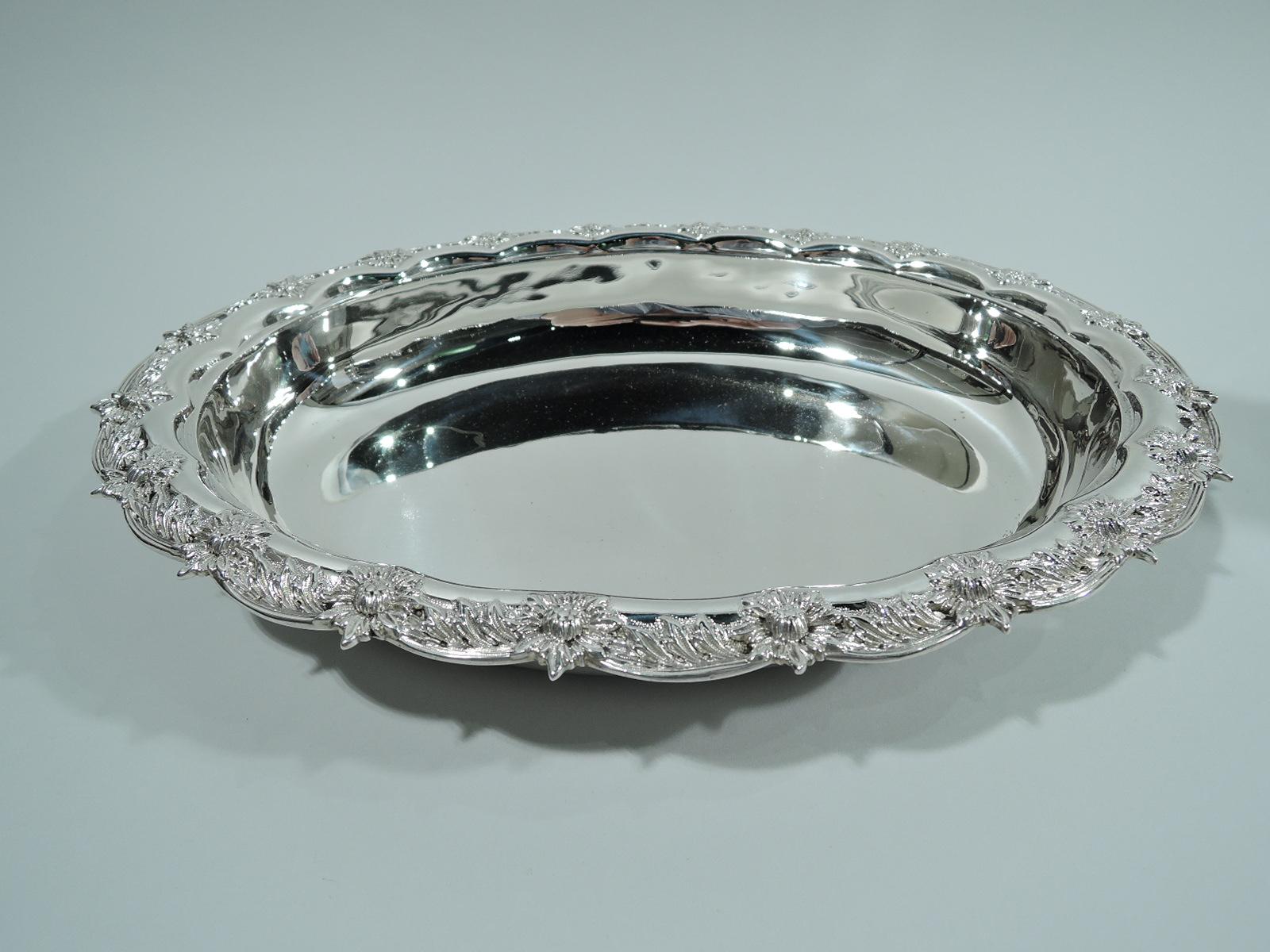 Chrysanthemum sterling silver serving bowl. Made by Tiffany & Co. in New York. Oval well with tapering sides, and scalloped rim with applied leaf-and-flower head border. A controlled arrangement in the historic Japonesque pattern. Fully marked