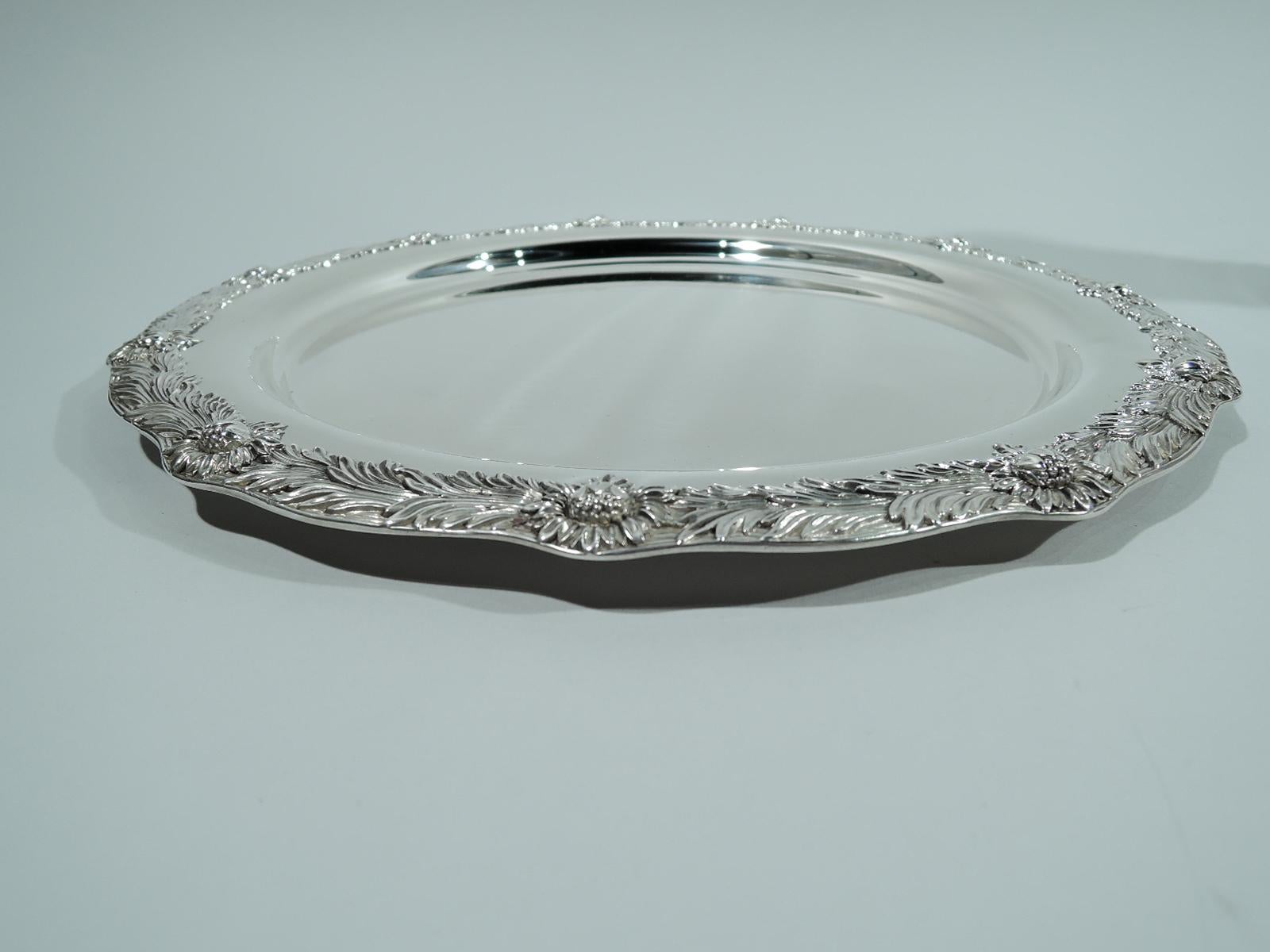 Chrysanthemum sterling silver tray. Made by Tiffany & Co. in New York, ca 1910. Round with plain well; shoulder has dense and orderly arrangement of flower heads and leaves. Gently wavy rim. A great piece in a desirable pattern that was first