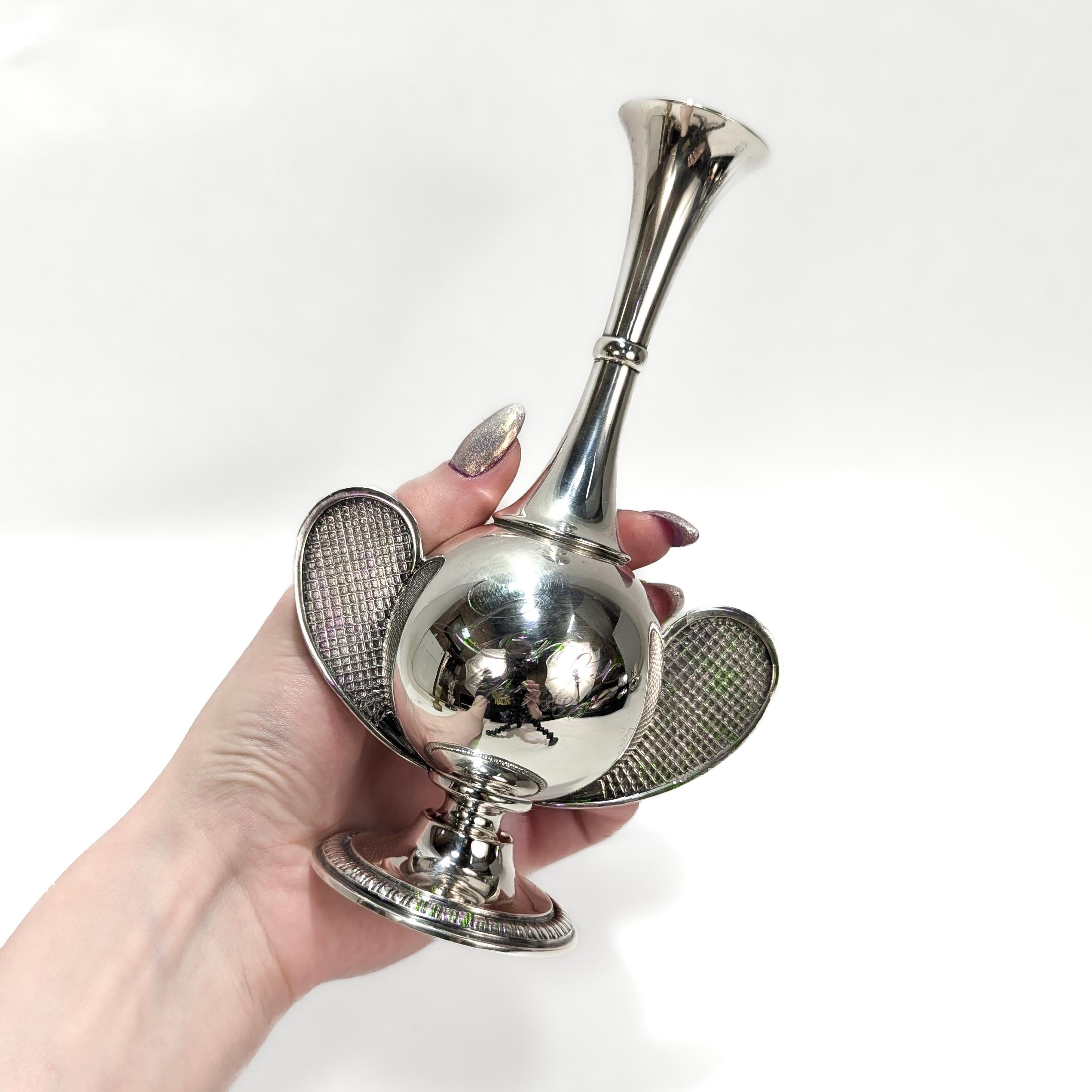 A fine antique sterling silver trophy for the Lenox Invitational Tennis tournamet. 

By Tiffany & Co.

In sterling silver.

With a trumpet foot, a bulbous body, a flared neck, and figural tennis racket handles to either side.

Engraved to the front: