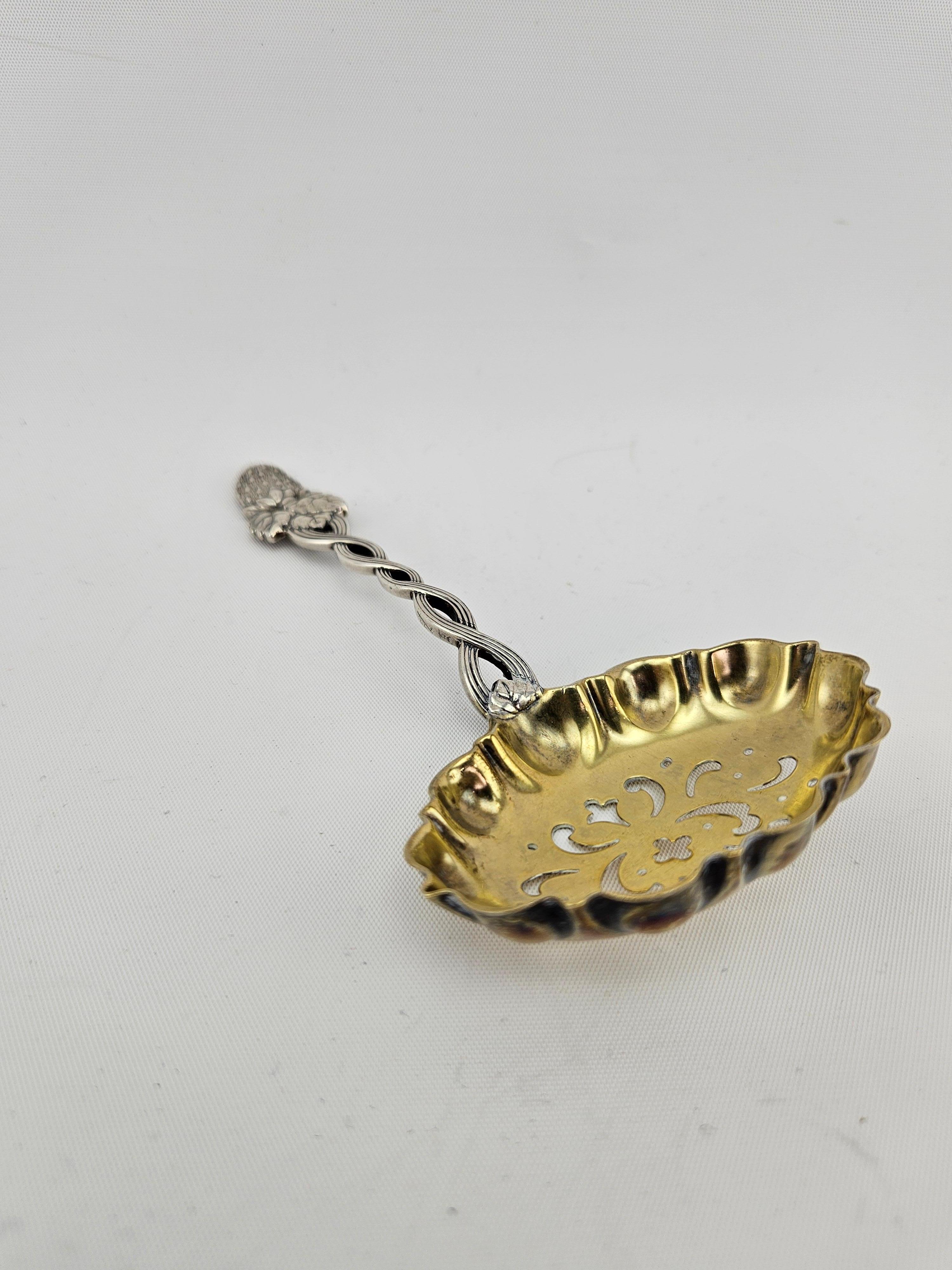Antigüedades Tiffany & Co. Tamiz de azúcar de plata de ley.  Diseño de enredadera de fresa muy decorativo con asa retorcida.  Hoja lavada en oro con algunos pequeños desgastes debidos a la edad y al uso.   Pesa 40 gramos.