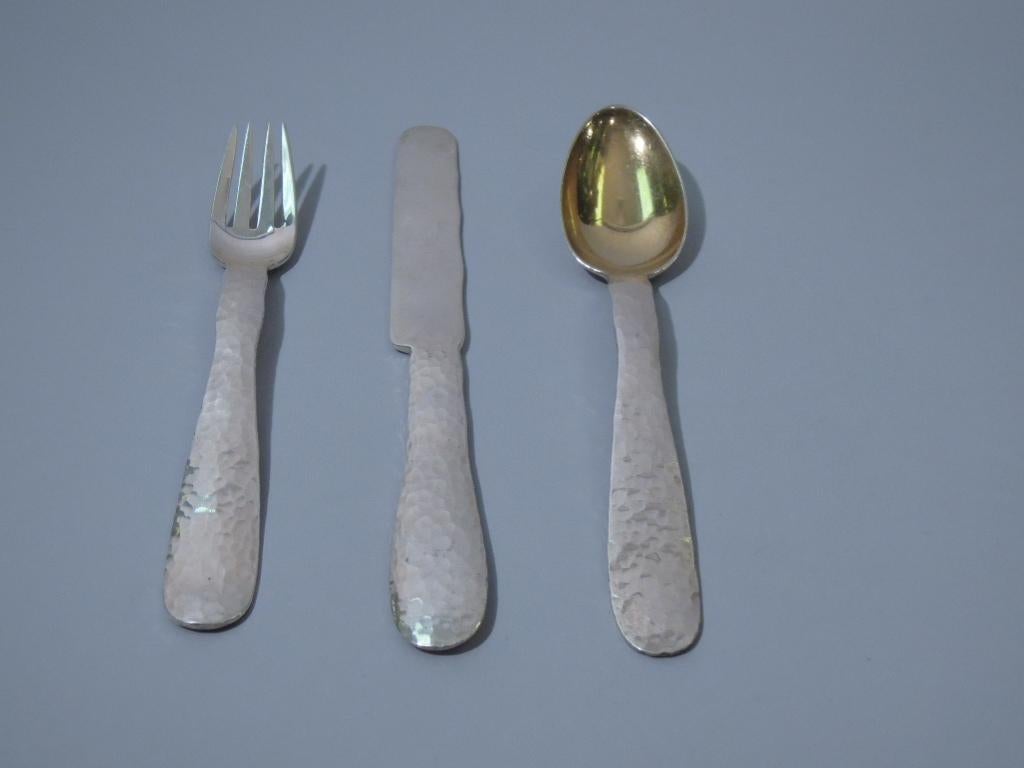 Craftsman sterling silver 3-piece youth place setting. Made by Tiffany, circa 1910. Hammered handles. Spoon bowl lightly gilt. Knife blade sterling silver. An example of the Craftsman influence on the American silver giant. Fully hallmarked.