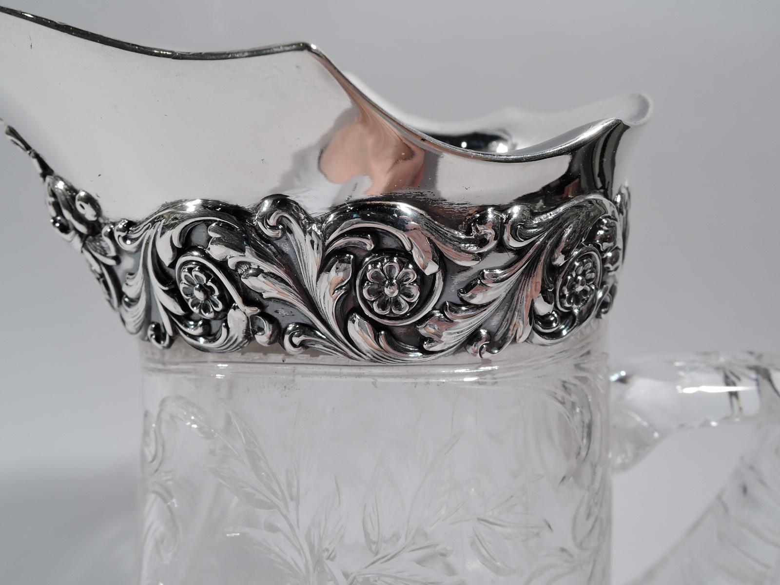 Edwardian Art Nouveau bar pitcher. Made by Tiffany & Co. in New York. Glass shaped and ovoid body with bracket handle and round and flat foot. Rock crystal-cut ornament: Leafing branches. On bottom: Flowers in ogee frames. On front armorial