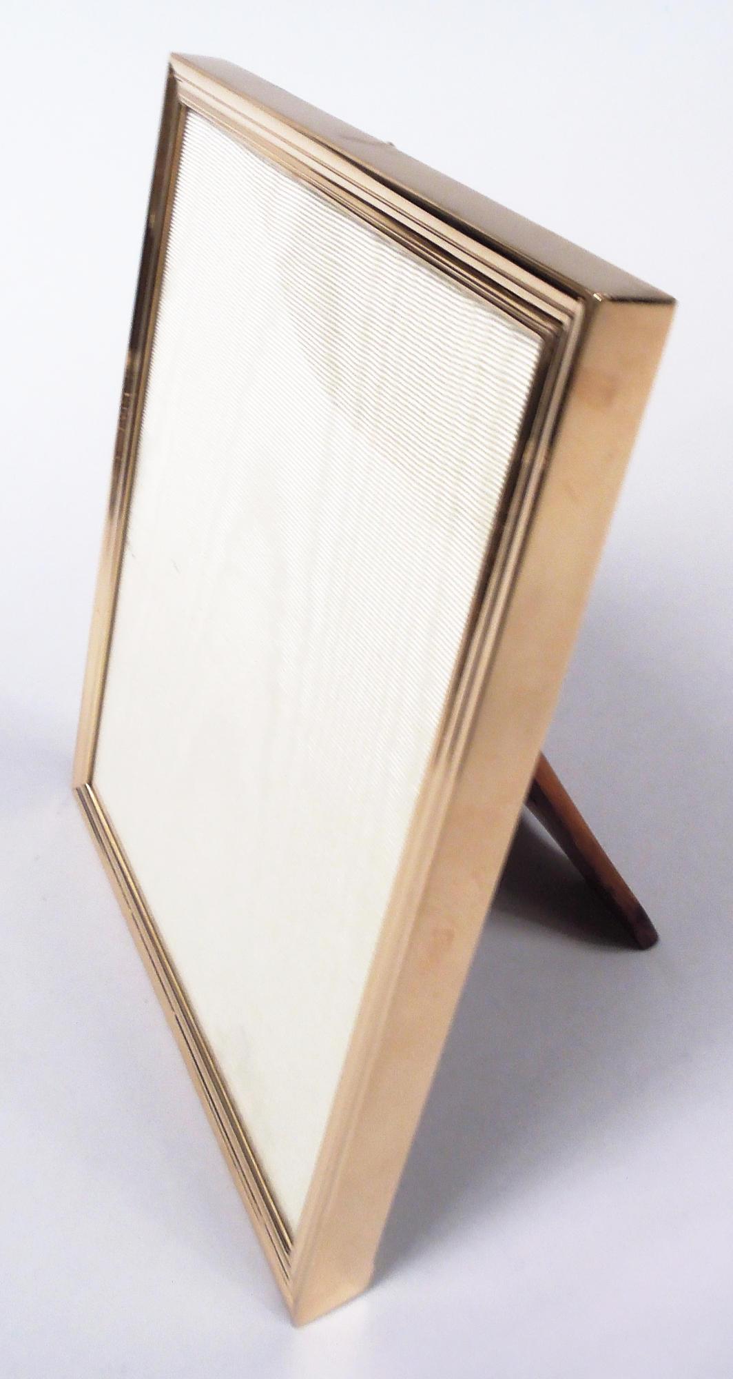 Edwardian Classical 14k gold picture frame. Made by Tiffany & Co. in New York, ca 1910. Rectangular window in molded surround; sides plain. With glass, silk lining, and stained-wood back and easel support for portrait (vertical) display. Fully