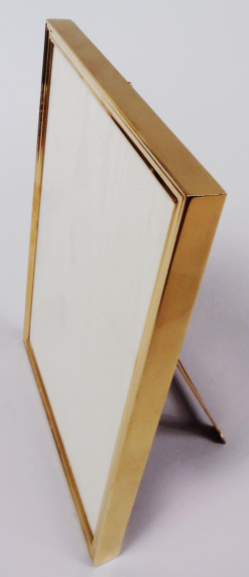 Edwardian Classical 18k gold picture frame. Made by Tiffany & Co. in New York, ca 1919. Rectangular window in molded surround; sides plain. With glass, silk lining, and stained-wood back and hinged gold easel support for portrait (vertical) display.