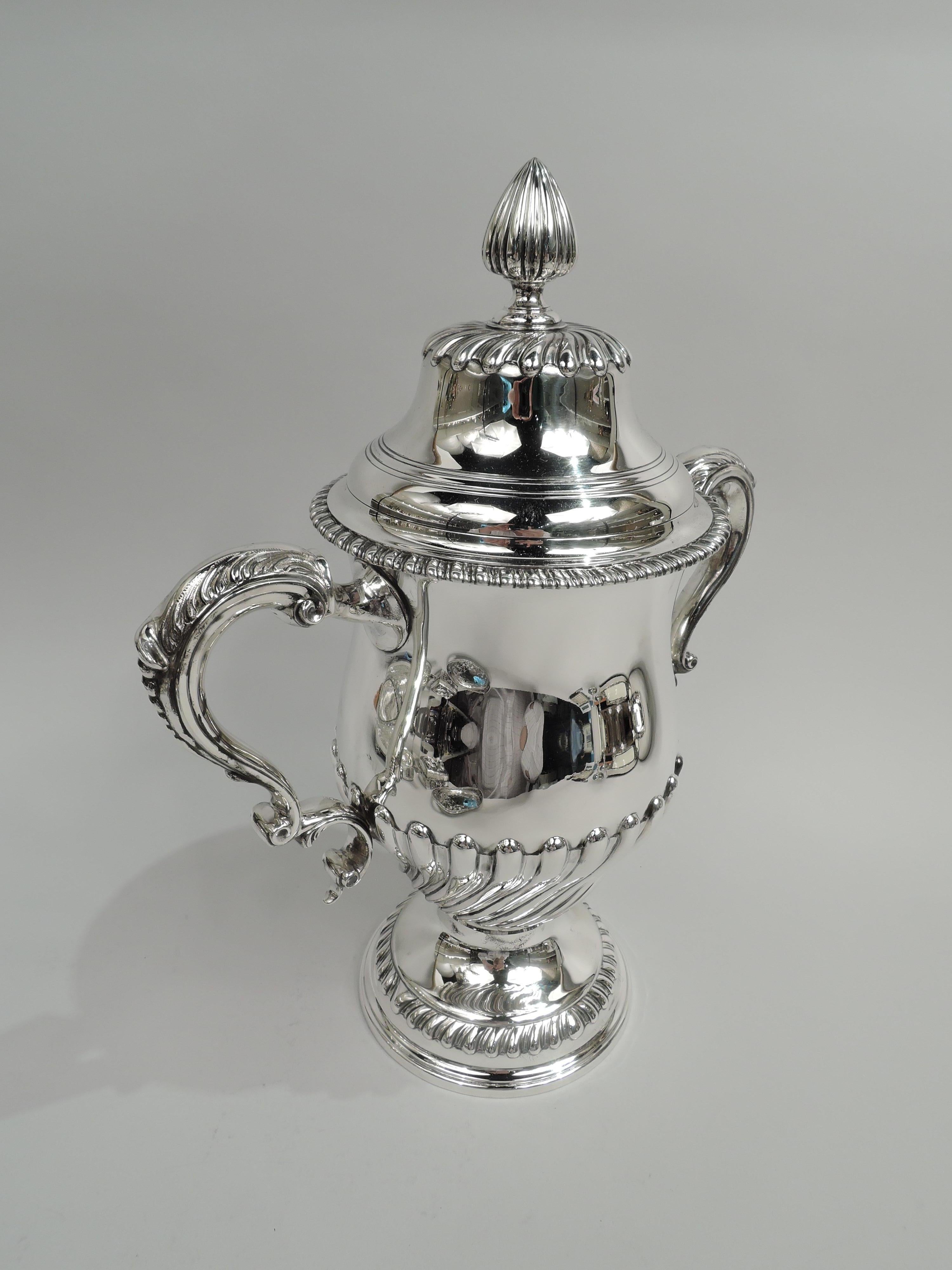 Edwardian Classical sterling silver covered urn. Made by Tiffany & Co. in New York, circa 1913. Ovoid bowl on domed foot. Leaf-capped double-scroll side handles. Cover domed with bud finial and incised rings. Gadrooning and twisted fluting.