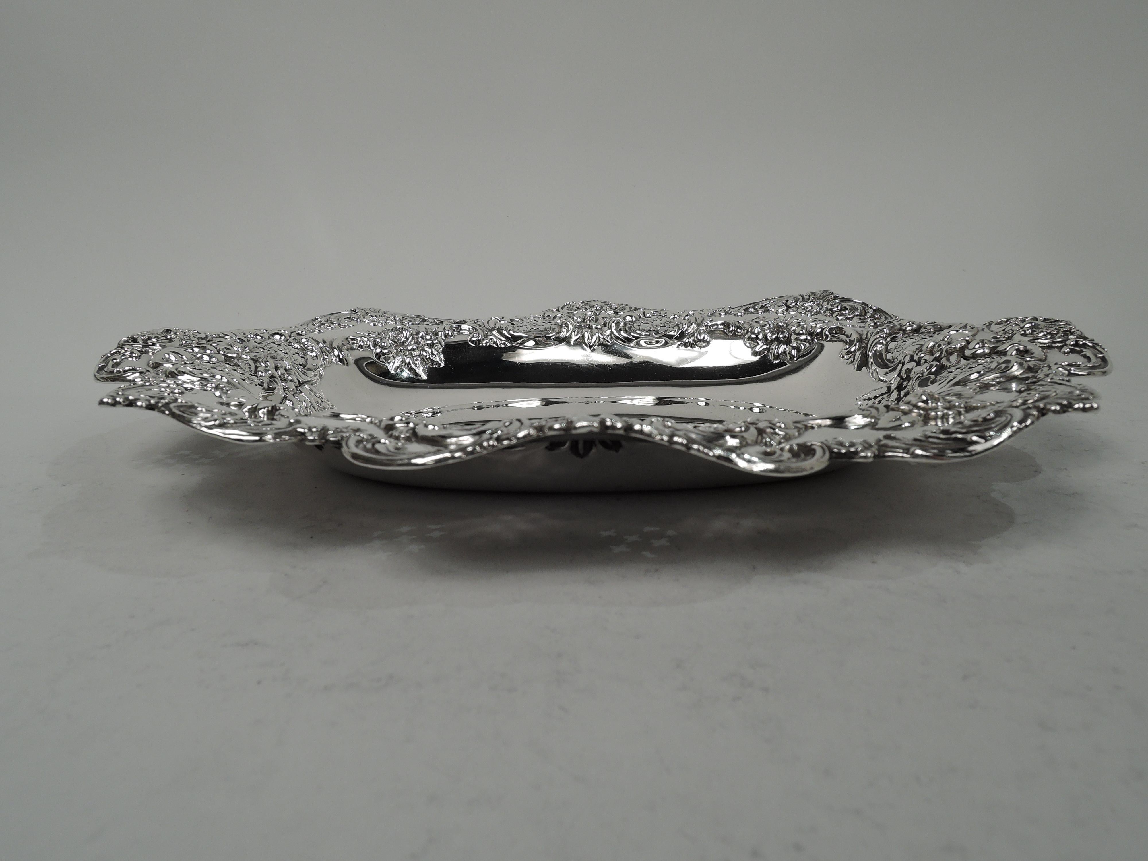 Edwardian Classical sterling silver bowl. Made by Tiffany & Co. in New York. Oval well with tapering sides and wavy, scrolled rim. Chased and cast scrolls, flowers, leaves, and scallop shells. Fully marked including maker’s stamp, pattern no. 14367,