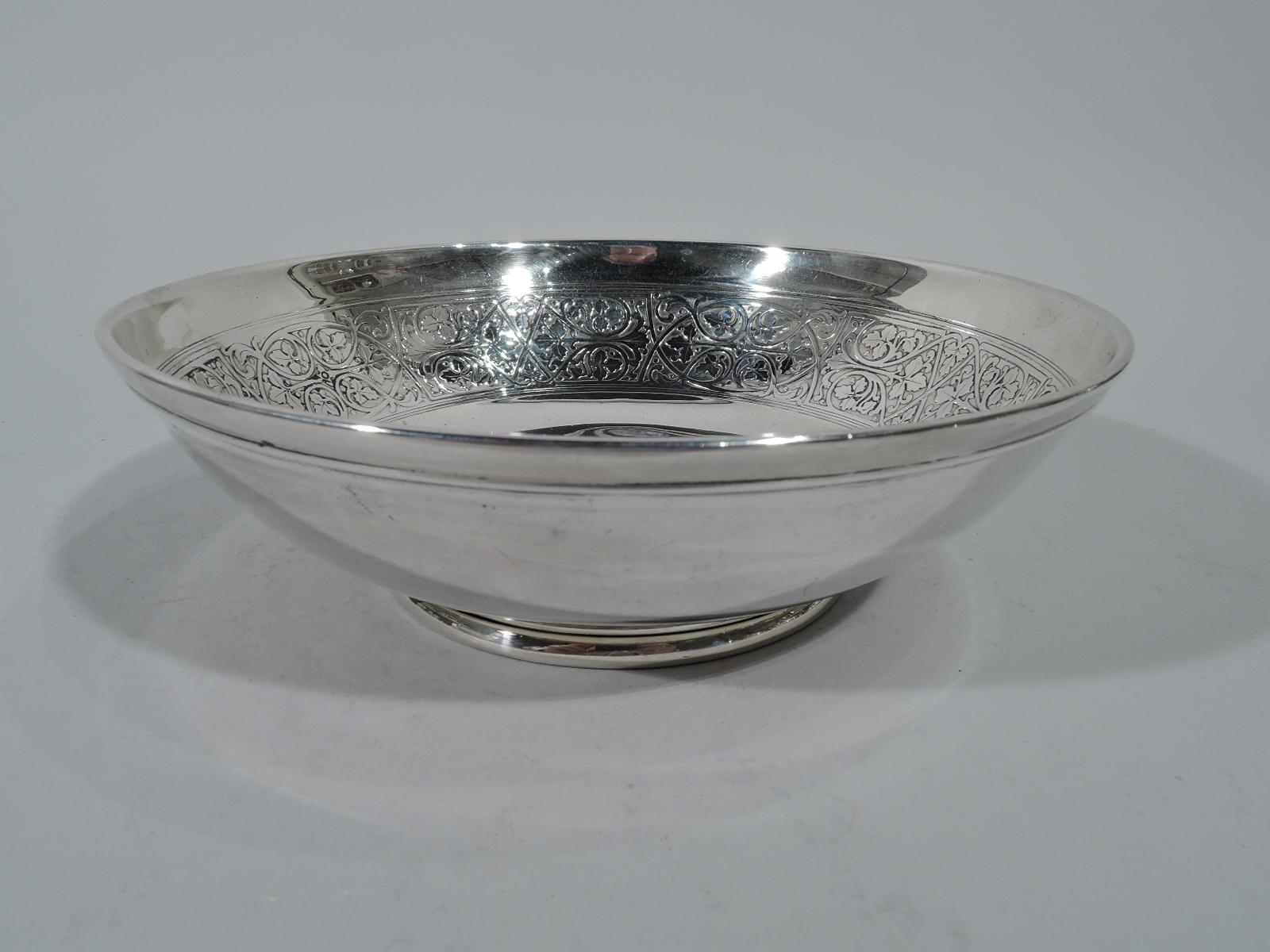 Edwardian sterling silver bowl. Made by Tiffany & Co. in New York. Curved sides, turned-down rim, and inset reeded foot. Interior has wide acid-etched band comprising curvilinear frame inset with stylized leaves. Wreath with same in center (vacant).