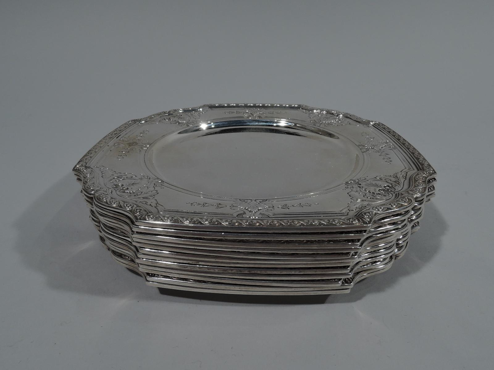 Twelve Edwardian bread and butter plates. Made by Tiffany & Co. in New York, circa 1916. Each plain circular well and four curved sides with double-scroll corners. Chased and engraved ornament: Fluid leaf set in scrolling-leaf frame alternating with