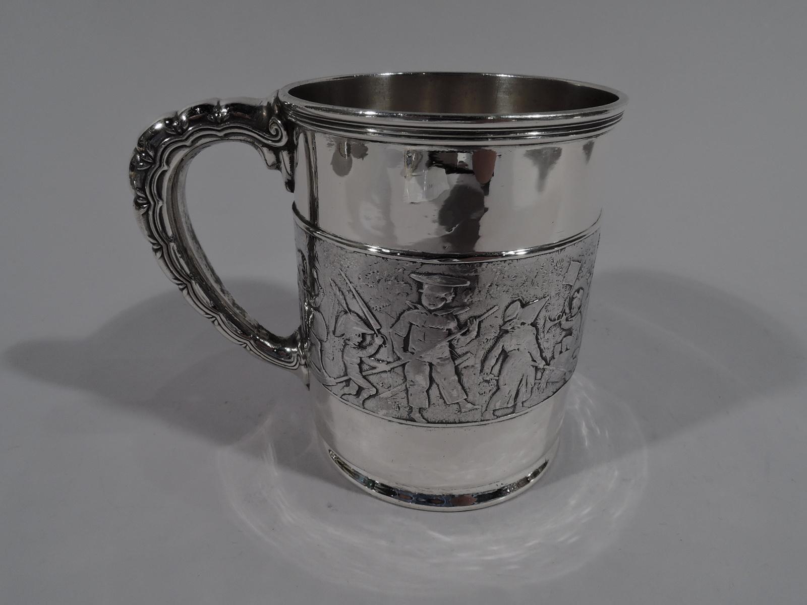 Edwardian sterling silver baby cup. Made by Tiffany & Co. in New York. Straight sides and lobed C-scroll handle. Chased frieze of children’s parade—a boisterous procession of boys and girls blowing bugles, jangling tambourines, and beating drums.