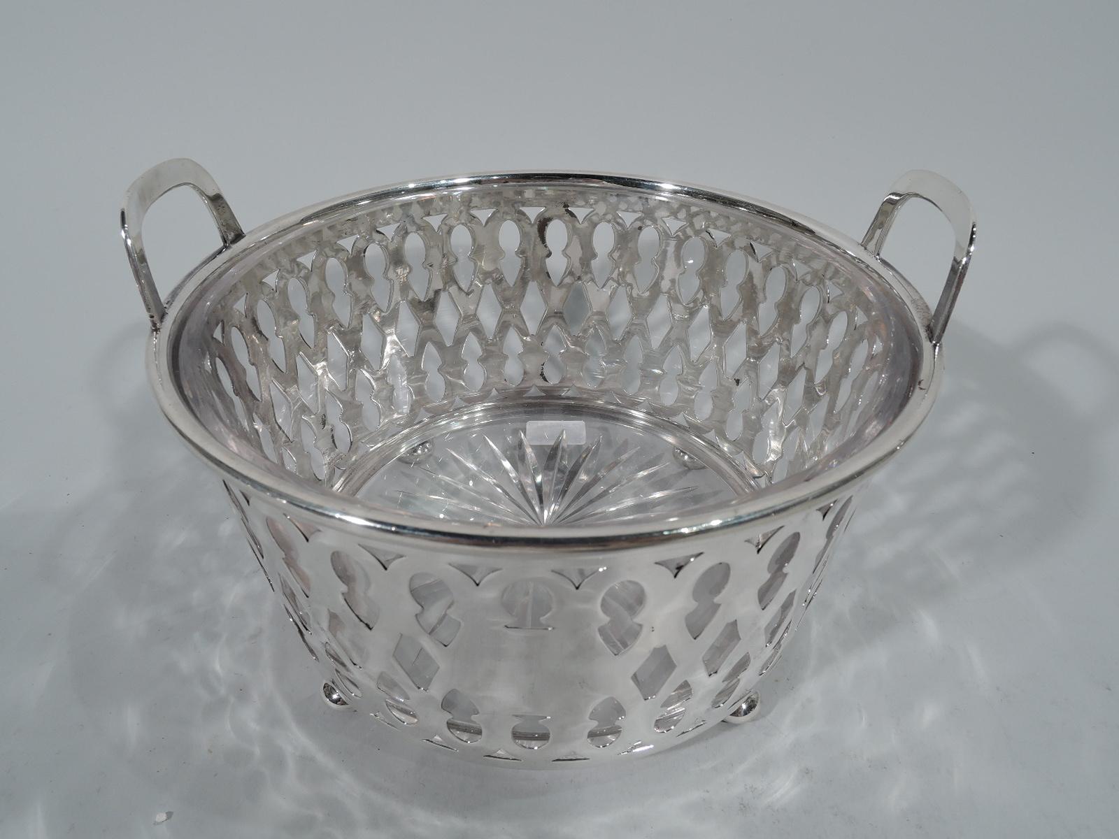 Edwardian sterling silver ice bucket. Made by Tiffany & Co. in New York. Straight and tapering sides with open bottom, four ball supports, and two bracket handles mounted to rim. Sides have repeating figure-eight motif with keyhole-style piercing.