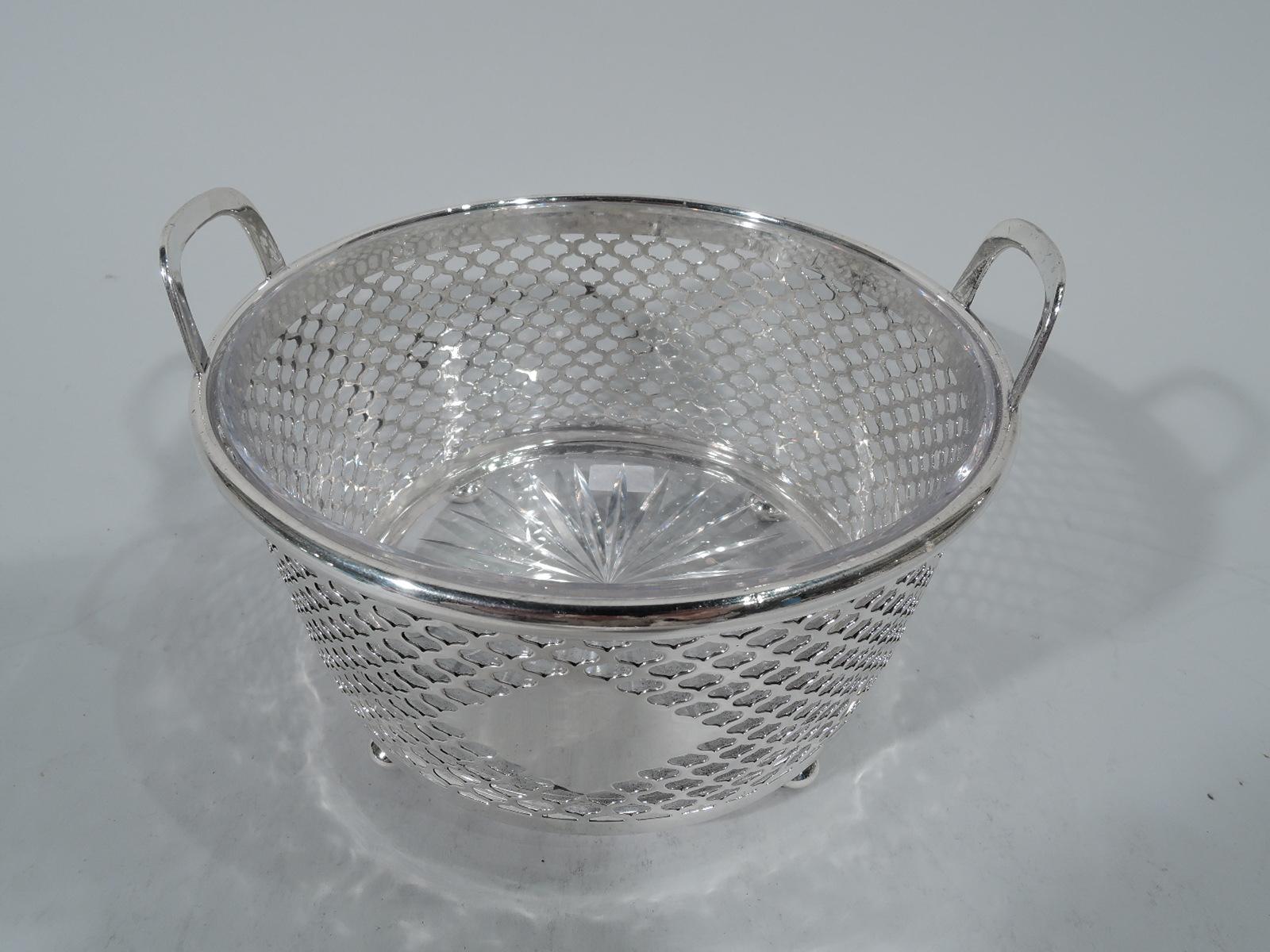 Edwardian sterling silver ice bucket. Made by Tiffany & Co. in New York. Straight and tapering sides with open bottom, four squashed ball supports, and two bracket handles mounted to rim. Sides have web-style piercing. Lozenge-form cartouche