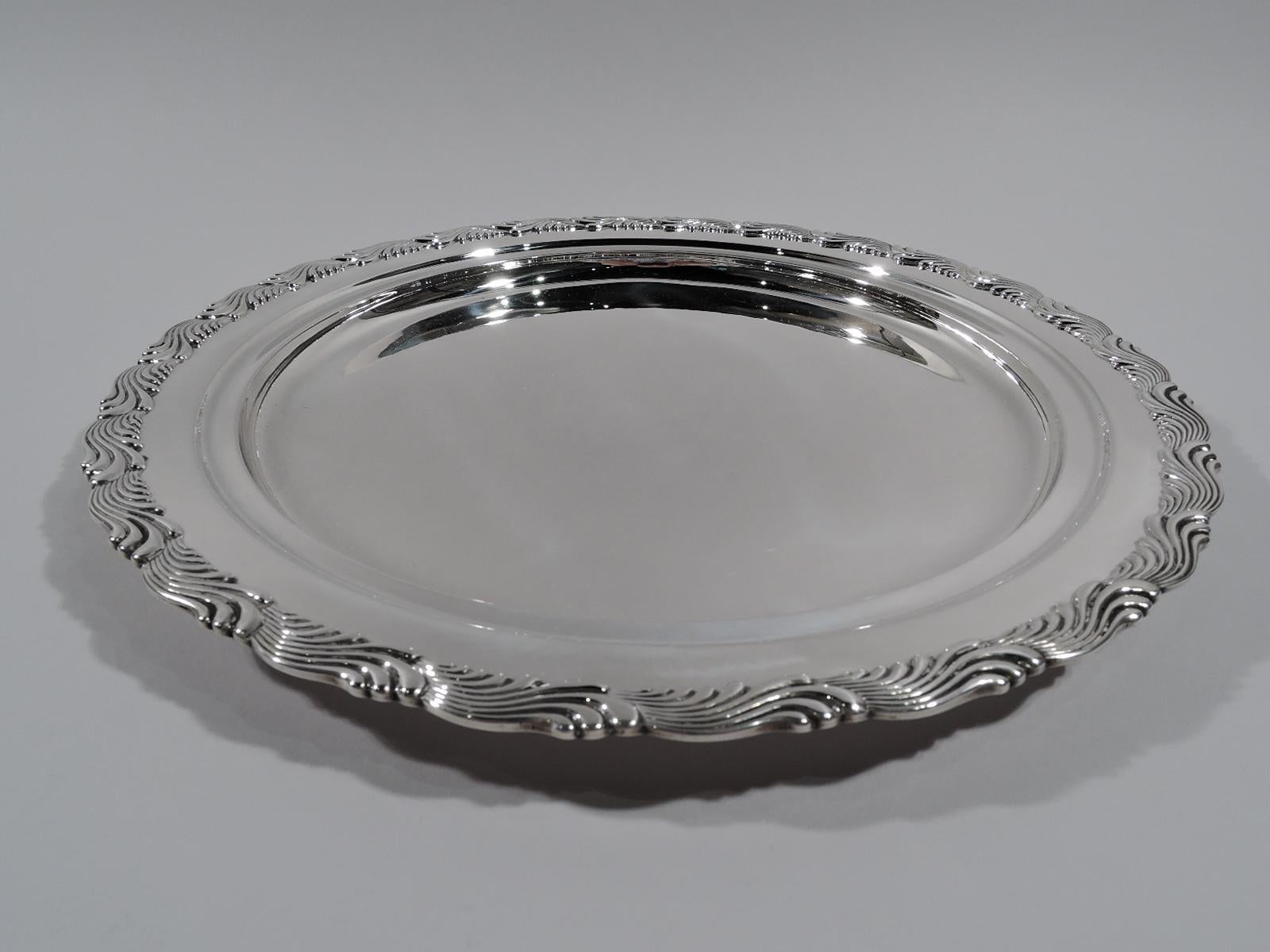Edwardian sterling silver tray. Made by Tiffany & Co. in New York. Deep well and stepped shoulder. Rim interior has chased border in form of imbricated leaves or chevrons. A popular motif that is sometimes known as Wave Edge. Stylish and