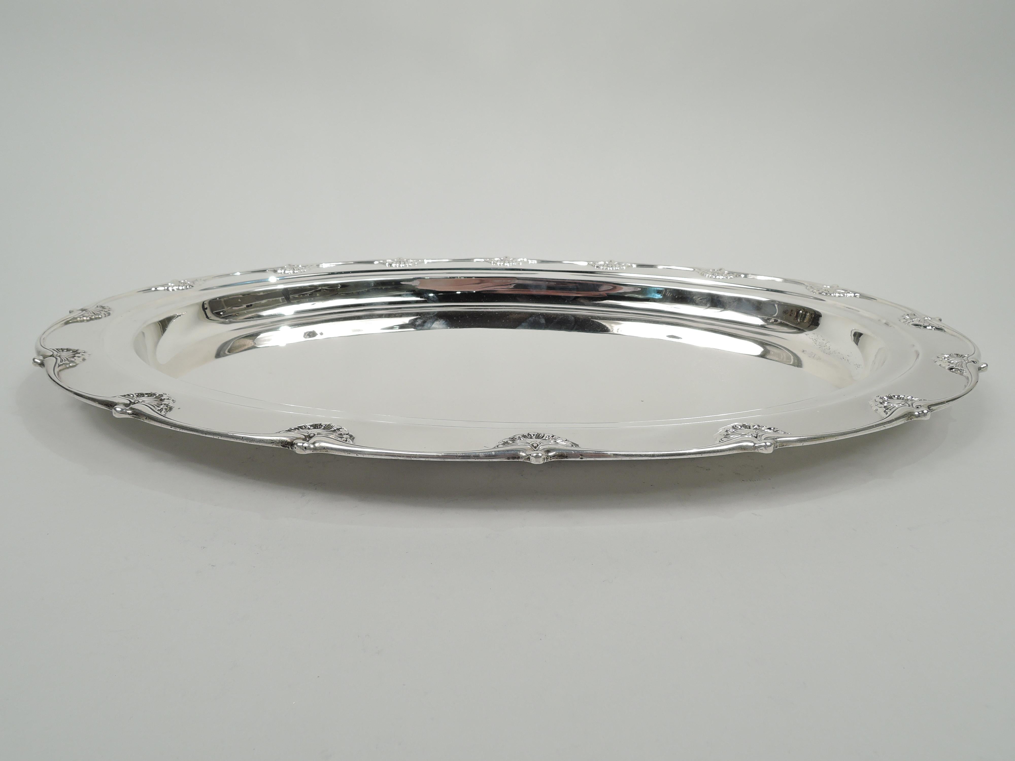 English King sterling silver serving tray. Made by Tiffany & Co. in New York. Oval well and wide and stepped shoulder. Applied gently undulating rim interspersed with scallop shells. Fully marked including maker’s stamp, pattern no. 11742, and