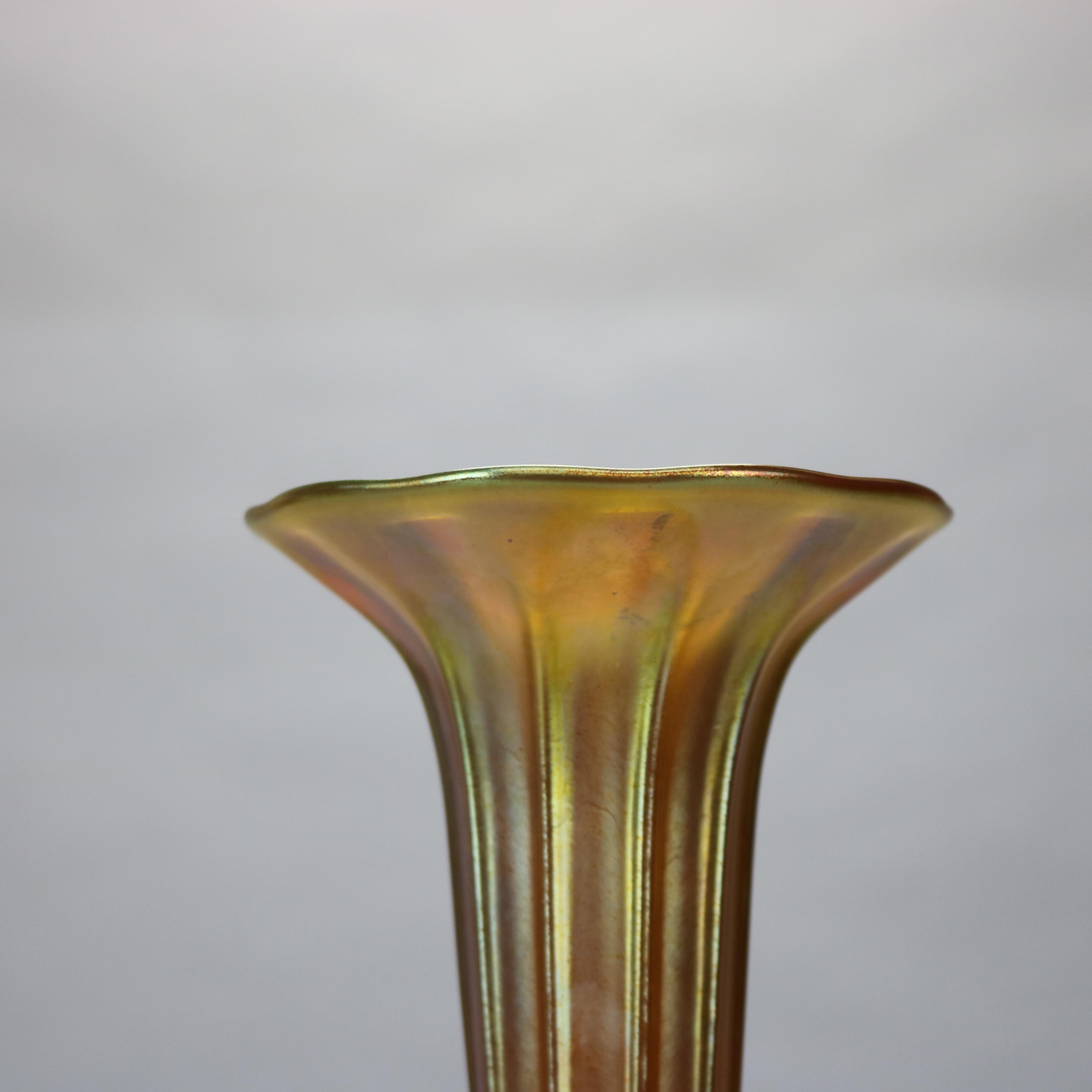 An antique fluted vase by Louis Tiffany Furnaces offers Favrile art glass in ribbed trumpet form seated in case bronze base having petal decoration, signed 
