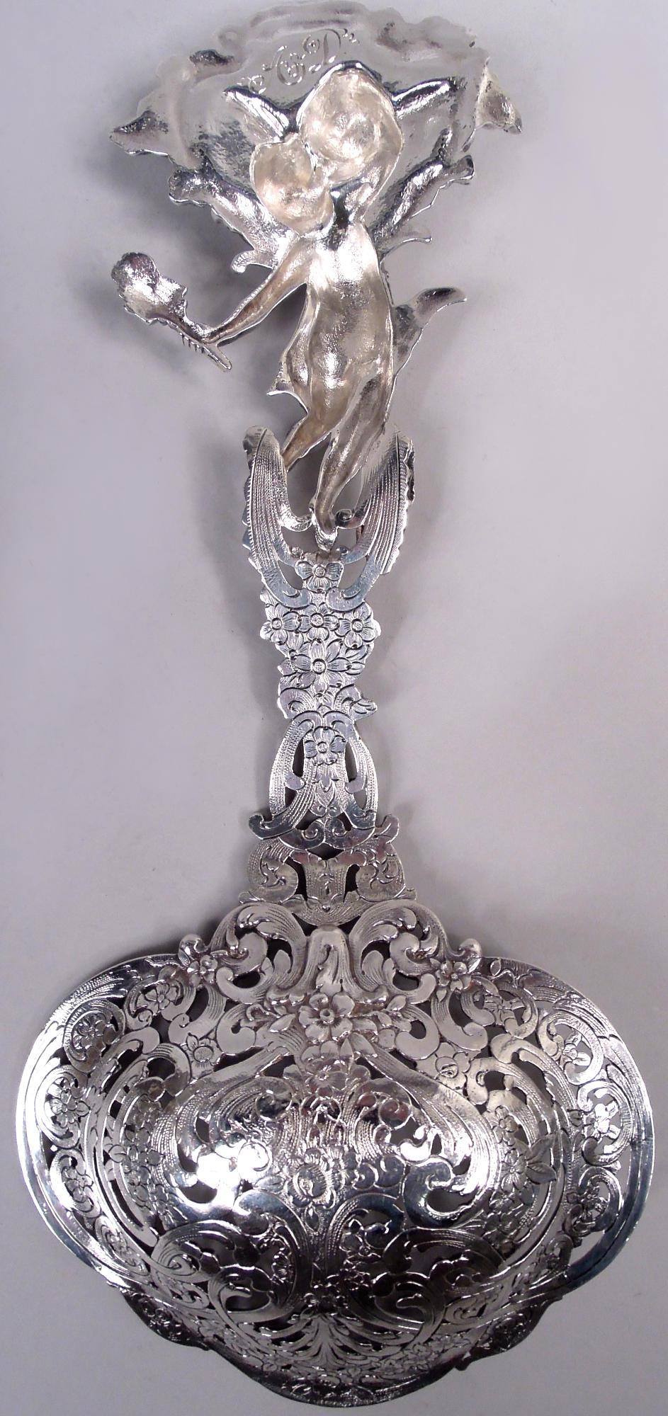 Pelle à bonbon classique en argent sterling de l'époque victorienne. Fabriqué par Tiffany & Co. à New York, ca. 1910. Coupe trilobée et rinceaux ouverts et fleurs. Terminal sous la forme d'un jeune homme portant une torche et vêtu d'une draperie,