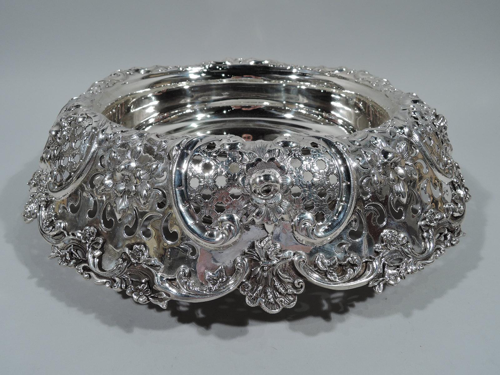 Large and fancy sterling silver centrepiece bowl. Made by Tiffany & Co. in New York, circa 1910. Solid round well. Wide turned-down rim with pierced, chased, and applied ornament, including flowers, diaper, scallop shells, and scrolls. The works.