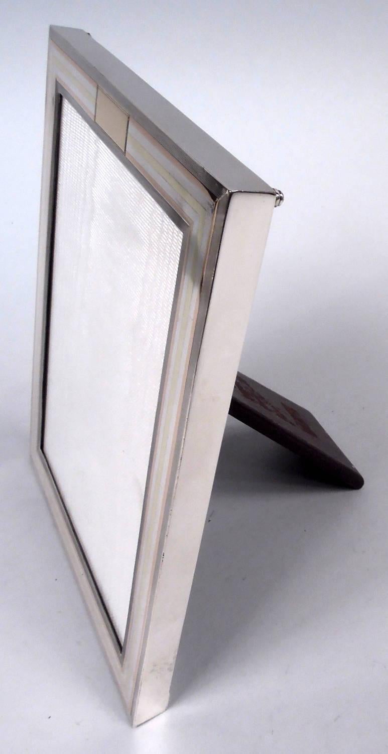 Marco moderno americano de plata de ley y oro de 14 quilates, hacia 1920. Comercializado por Tiffany & Co. en Nueva York. Ventana rectangular con marco plano de plata. El anverso tiene el borde redondeado y bandas envolventes de oro rosa y amarillo;